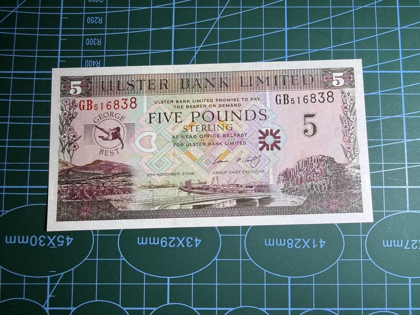 【炜奕收藏】，第五十六期，大不列颠专场 2006年北爱尔兰阿尔斯特银行5镑纪念钞，UNC品相，左下角有一个潮点，号码无47尾8，纪念足球明星乔治·贝斯特