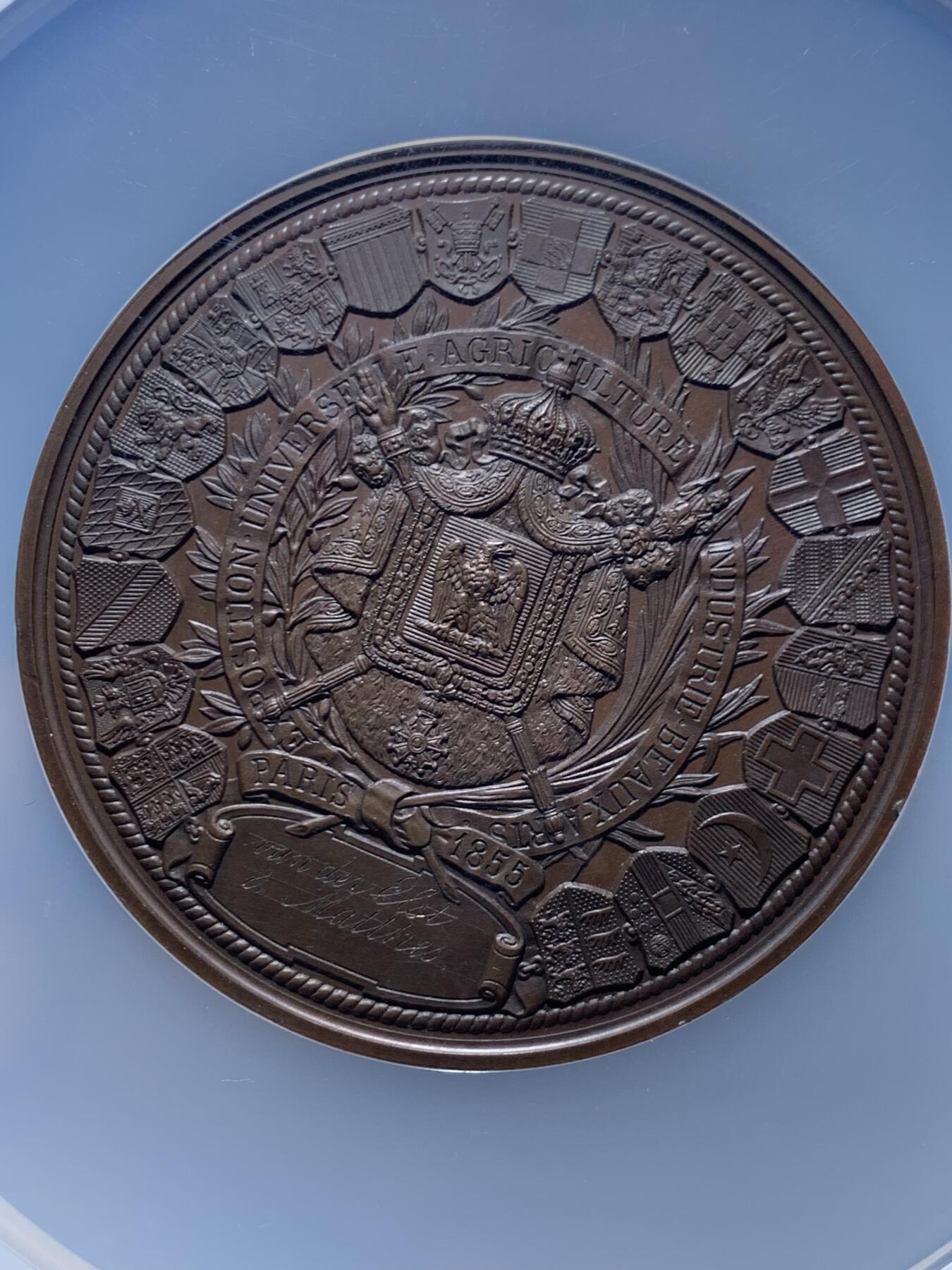 《竞宝斋》第457场 周日，周一，周二   3场连拍 （全场包邮）欢迎送拍 NGC MS64BN 法国1855年巴黎世博会纪念大铜章 60mm（签名版）定制款稀缺品，顶级高分，拿三章牌中的热门品种，20国徽章环绕波拿巴家族鹰徽，众星捧月，繁复华丽，记录拿破仑三世的巅峰时刻。手指边铭原铸品，加大加厚盒装。