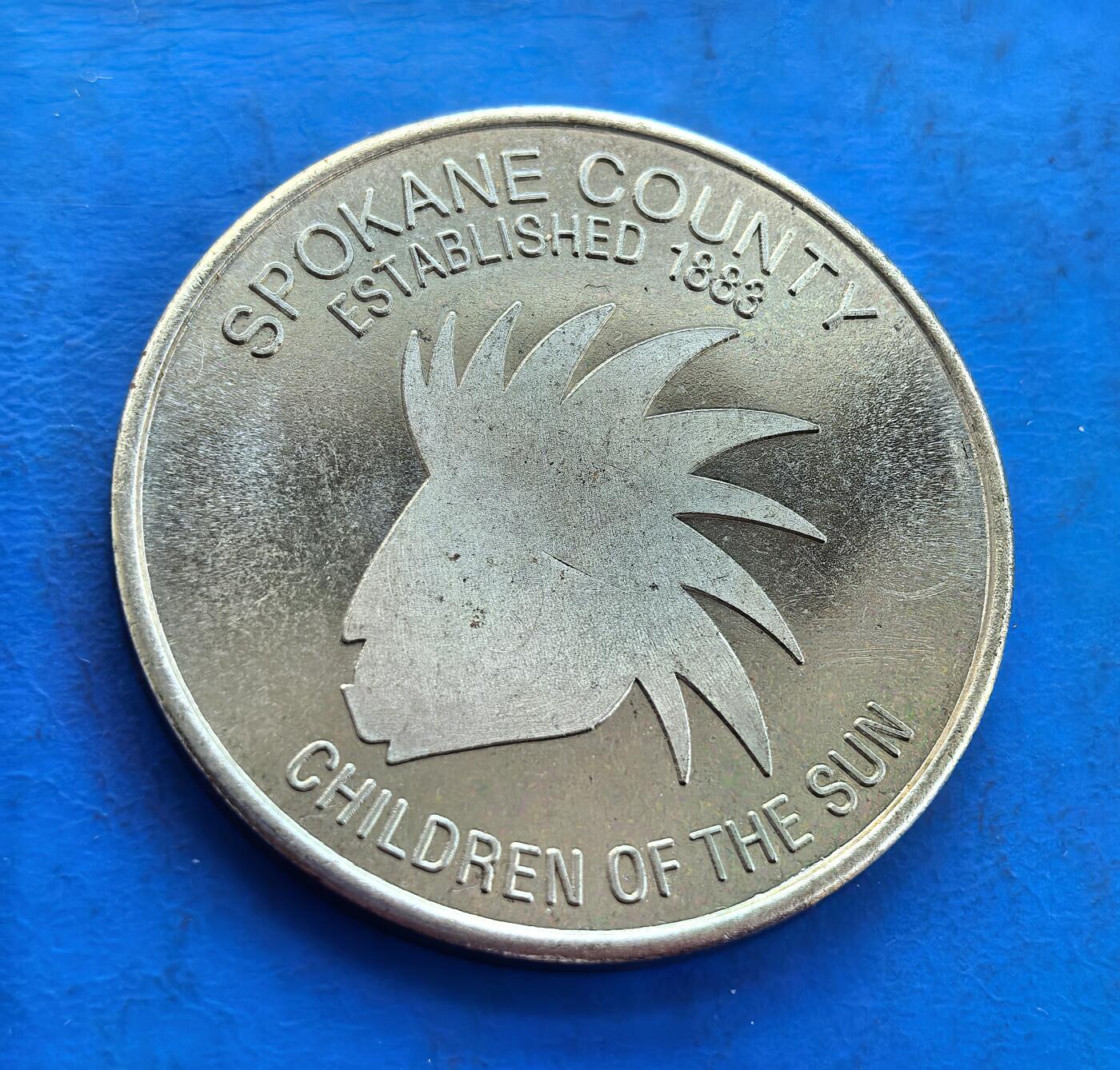 外国优质银币南亚香港苏联等专场，周六九点倒数截拍，满百包邮，持续收拍 发行量仅2000枚，美国华盛顿州斯波坎县的建州百年纪念币（直径40mm，重21.8克），搭配州花、雷尼尔山与飞鸟浮雕；呈现当地原住民 “太阳之子” 的标志性剪影。细腻包浆承载地域历史与文化，兼具纪念与收藏价值，是美国地方纪念币的特色品类
