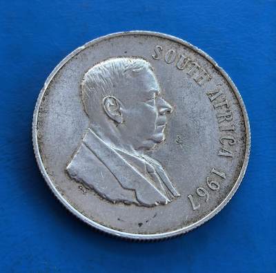 外国优质银币南亚香港苏联等专场，周六九点倒数截拍，满百包邮，持续收拍 - 南非1967 年 1 兰特银币，正面是南非总理亨德里克・弗伦施・维沃尔德的侧面像，轮廓清晰，展现政治人物的沉稳气质；背面为跳跃的黑斑羚浮雕，搭配 “1 RAND” 与拉丁文 “SOLI DEO GLORIA”（荣耀归于神），承载南非历史印记，银质包浆温润，兼具收藏与历史价值。