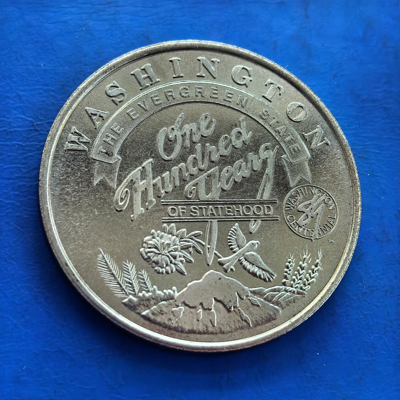 外国优质银币南亚香港苏联等专场，周六九点倒数截拍，满百包邮，持续收拍 发行量仅2000枚，美国华盛顿州斯波坎县的建州百年纪念币（直径40mm，重21.8克），搭配州花、雷尼尔山与飞鸟浮雕；呈现当地原住民 “太阳之子” 的标志性剪影。细腻包浆承载地域历史与文化，兼具纪念与收藏价值，是美国地方纪念币的特色品类