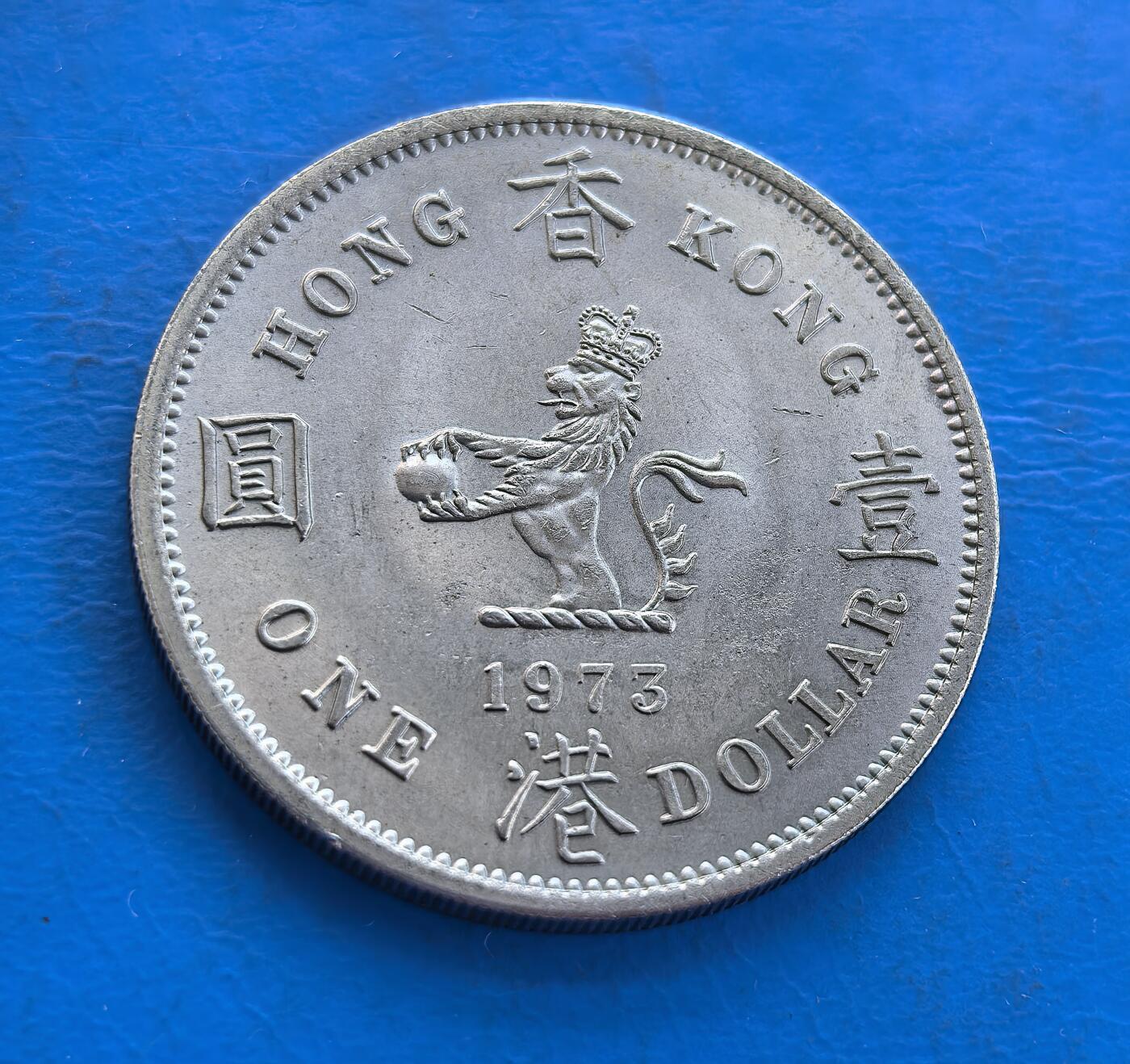 外国优质银币南亚香港苏联等专场，周六九点倒数截拍，满百包邮，持续收拍 原光1973年香港壹圆，正面为英女王伊丽莎白二世侧面像，环刻 “ELIZABETH THE SECOND QUEEN” 字样；背面是戴皇冠的狮子图案，搭配 “香港 壹圆” 字样与英文 “ONE DOLLAR”。原光包浆保留出厂光泽，见证英属香港末期货币历史，是近代殖民钱币收藏的优质品类。