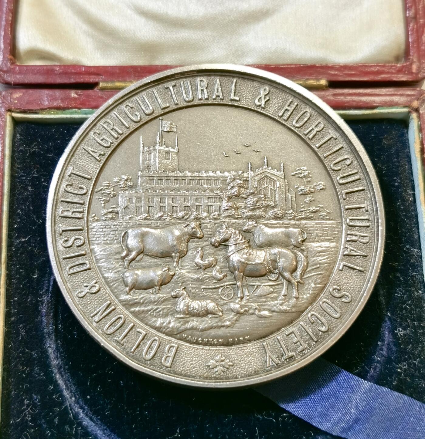 甄臻铺-世界币章拍卖（第48期）精品场拍品征集中，送拍享返佣金等优惠多多 1910年英国Bolton & District Agricultural & Horticultural Society农业园艺协会颁发的银质奖章，直径51.5毫米，重56.8克，带原装红皮盒。奖章正面刻有协会名称、建筑、牛马等农业元素，背面环绕麦穗花环，中心有双头鹰图案，细节丰富，工艺精致。