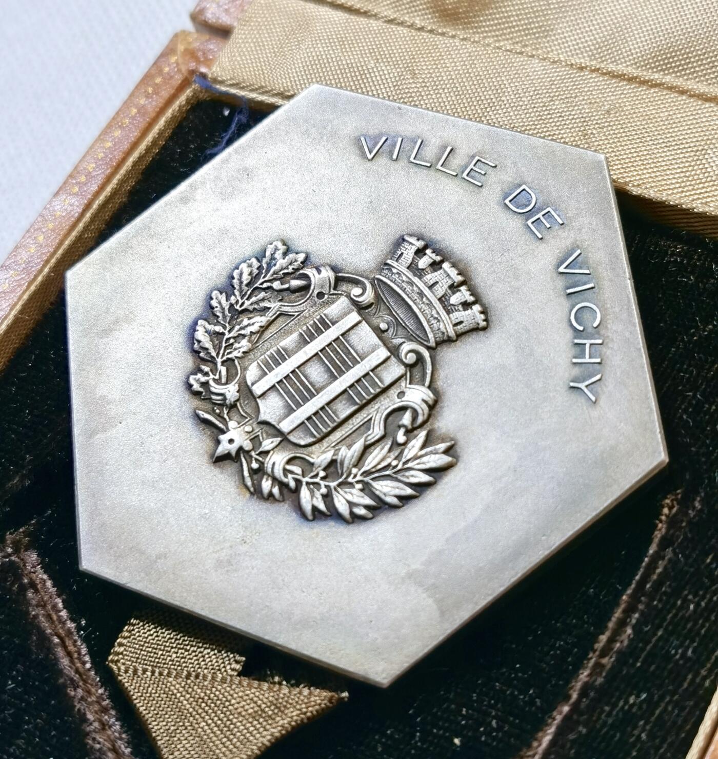 甄臻铺-世界币章拍卖（第48期）精品场拍品征集中，送拍享返佣金等优惠多多 法国山泉小镇纪念章，法国著名的山泉小镇维希市城市纪念章，雕刻画面是著名的古典油画《泉》。材质不明，可能是铜镀银或者银章，无边铭，直径61mm，重量98.4g，品相完美，有完好原盒，如图。