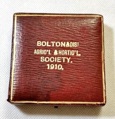 甄臻铺-世界币章拍卖（第48期）精品场拍品征集中，送拍享返佣金等优惠多多 - 1910年英国Bolton & District Agricultural & Horticultural Society农业园艺协会颁发的银质奖章，直径51.5毫米，重56.8克，带原装红皮盒。奖章正面刻有协会名称、建筑、牛马等农业元素，背面环绕麦穗花环，中心有双头鹰图案，细节丰富，工艺精致。