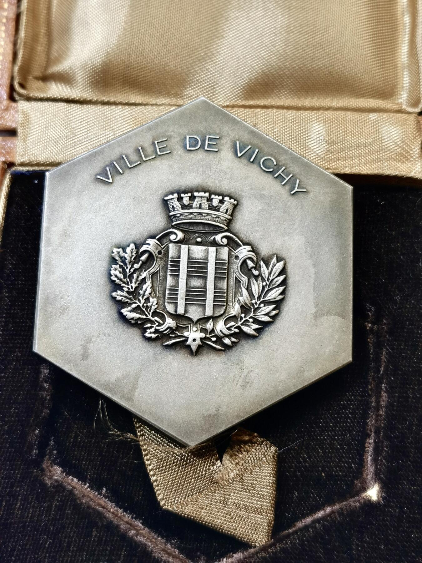 甄臻铺-世界币章拍卖（第48期）精品场拍品征集中，送拍享返佣金等优惠多多 法国山泉小镇纪念章，法国著名的山泉小镇维希市城市纪念章，雕刻画面是著名的古典油画《泉》。材质不明，可能是铜镀银或者银章，无边铭，直径61mm，重量98.4g，品相完美，有完好原盒，如图。