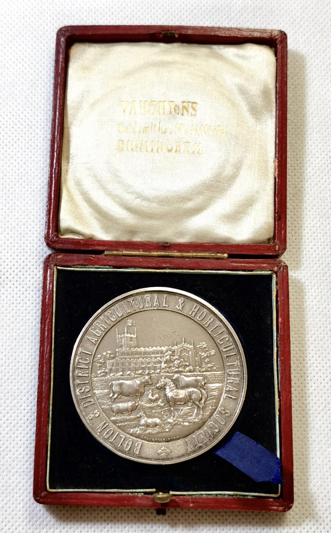 甄臻铺-世界币章拍卖（第48期）精品场拍品征集中，送拍享返佣金等优惠多多 1910年英国Bolton & District Agricultural & Horticultural Society农业园艺协会颁发的银质奖章，直径51.5毫米，重56.8克，带原装红皮盒。奖章正面刻有协会名称、建筑、牛马等农业元素，背面环绕麦穗花环，中心有双头鹰图案，细节丰富，工艺精致。