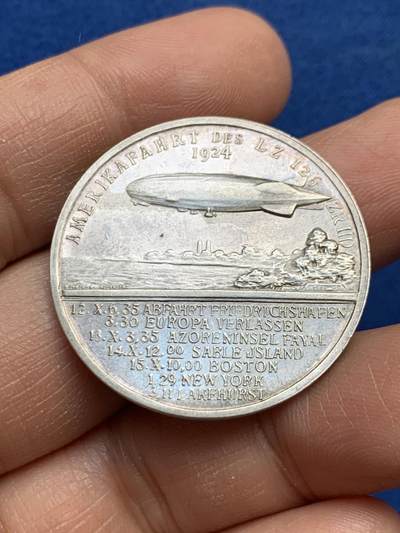 《竞宝斋》第459场 周日，周一，2场连拍 （全场包邮）欢迎送拍 - 德国雨果·埃克纳纪念银章，他是20世纪初飞艇技术的重要推动者，曾担任齐柏林飞艇公司的负责人，并亲自驾驶“兴登堡号”等著名飞艇完成多次跨大西洋飞行。该章背面详细列出了飞艇的行程时间表，包括从弗里德里希港出发、离开欧洲、经过亚速尔群岛法亚尔、到达萨布尔岛、波士顿、纽约和莱克赫斯特的具体日期和时间。14.92克，33.3mm，带990银标。