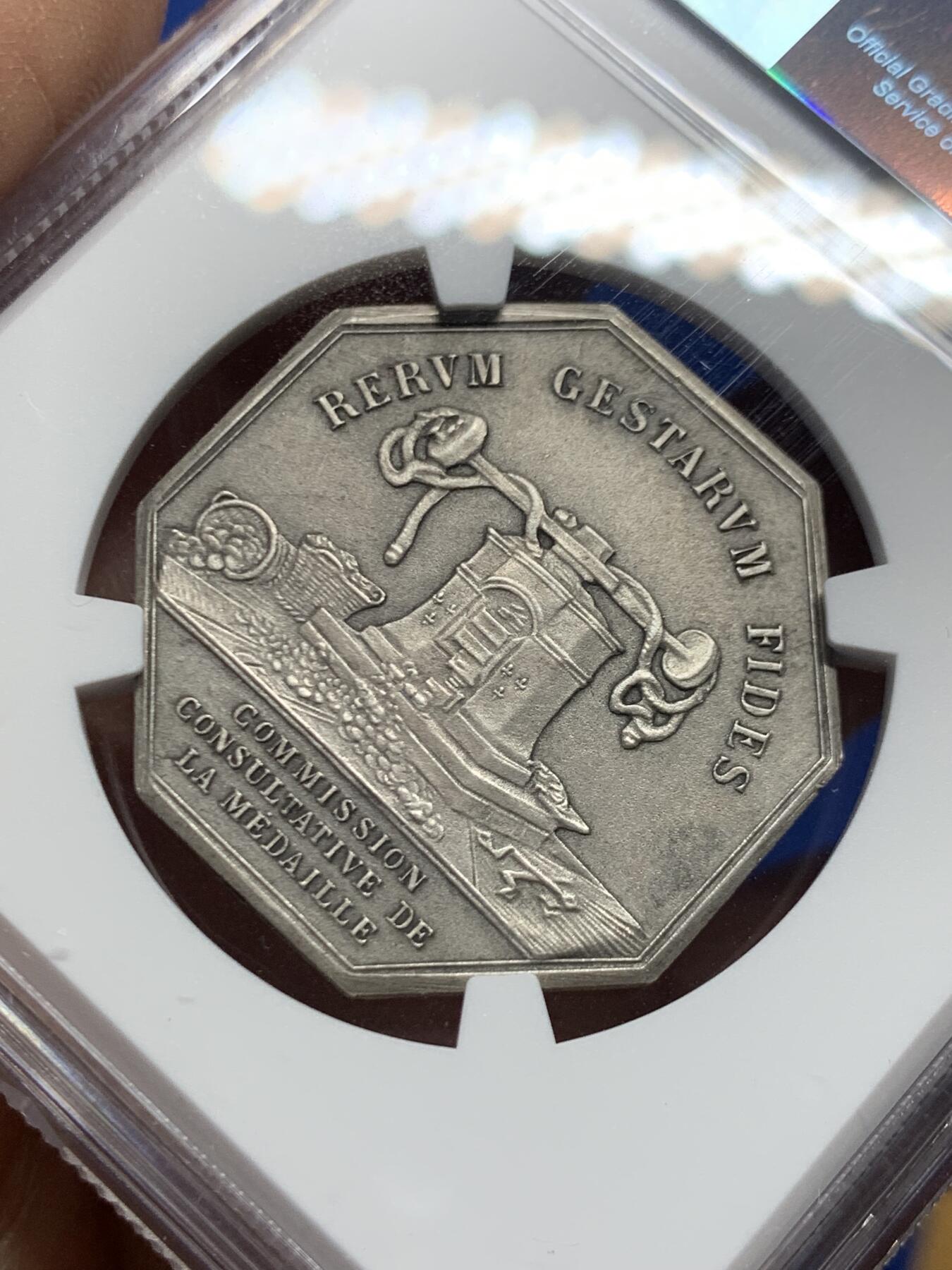 《竞宝斋》第460场 周日，周一，2场连拍 （全场包邮）欢迎送拍 NGC MS63 法国八角镀银铜质代币，正面雕刻一位羽翼女神(胜利或命运女神)牵引着小天使(爱神丘比特)，象征着命运引导下的爱与希望，左侧为撒落的丰收之角(Cornucopia)，右下角有艺术家名“DE PUYMAURIN”与雕刻标记，与整体构图共同形成寓言式场景。