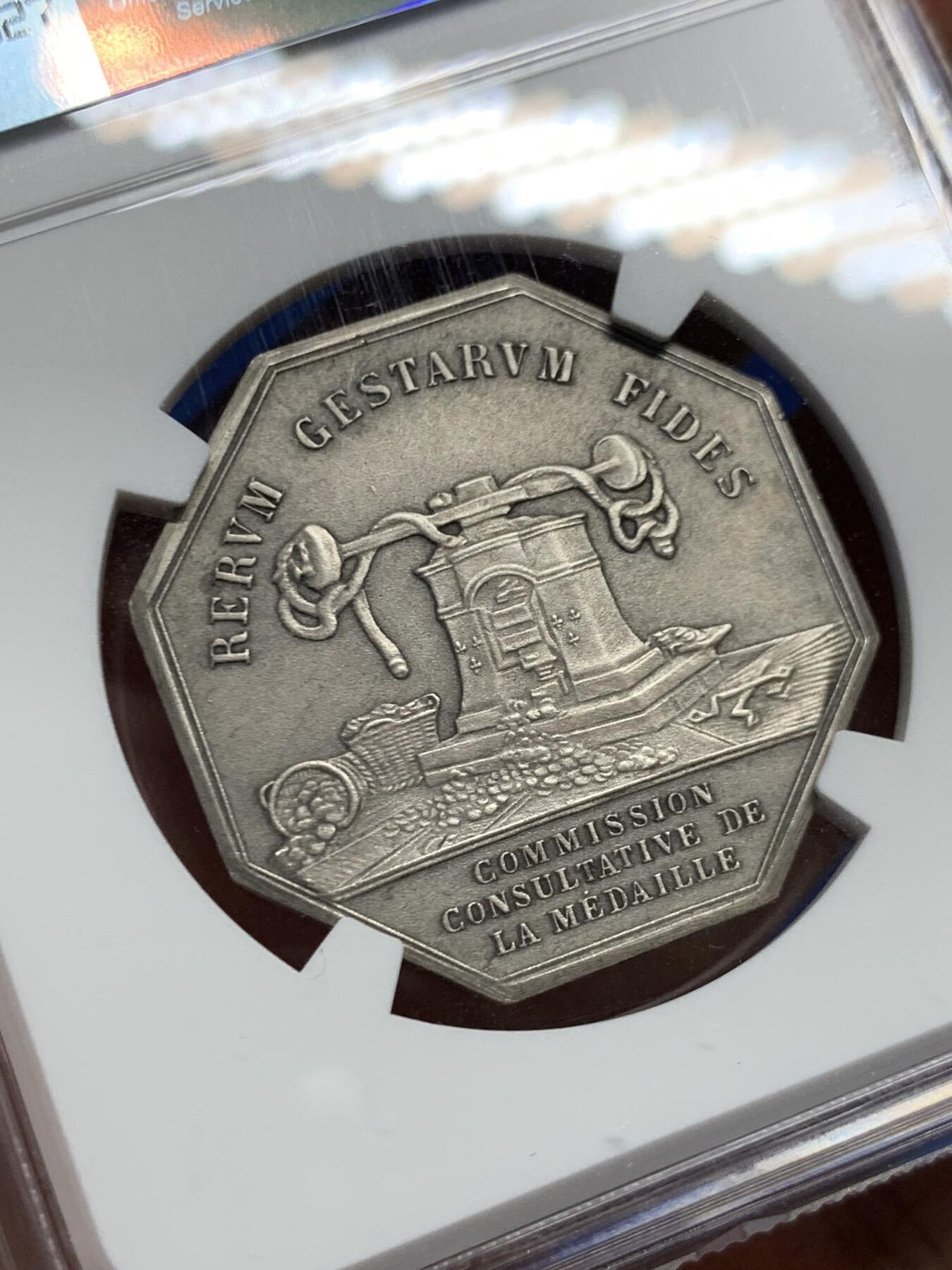 《竞宝斋》第460场 周日，周一，2场连拍 （全场包邮）欢迎送拍 NGC MS63 法国八角镀银铜质代币，正面雕刻一位羽翼女神(胜利或命运女神)牵引着小天使(爱神丘比特)，象征着命运引导下的爱与希望，左侧为撒落的丰收之角(Cornucopia)，右下角有艺术家名“DE PUYMAURIN”与雕刻标记，与整体构图共同形成寓言式场景。