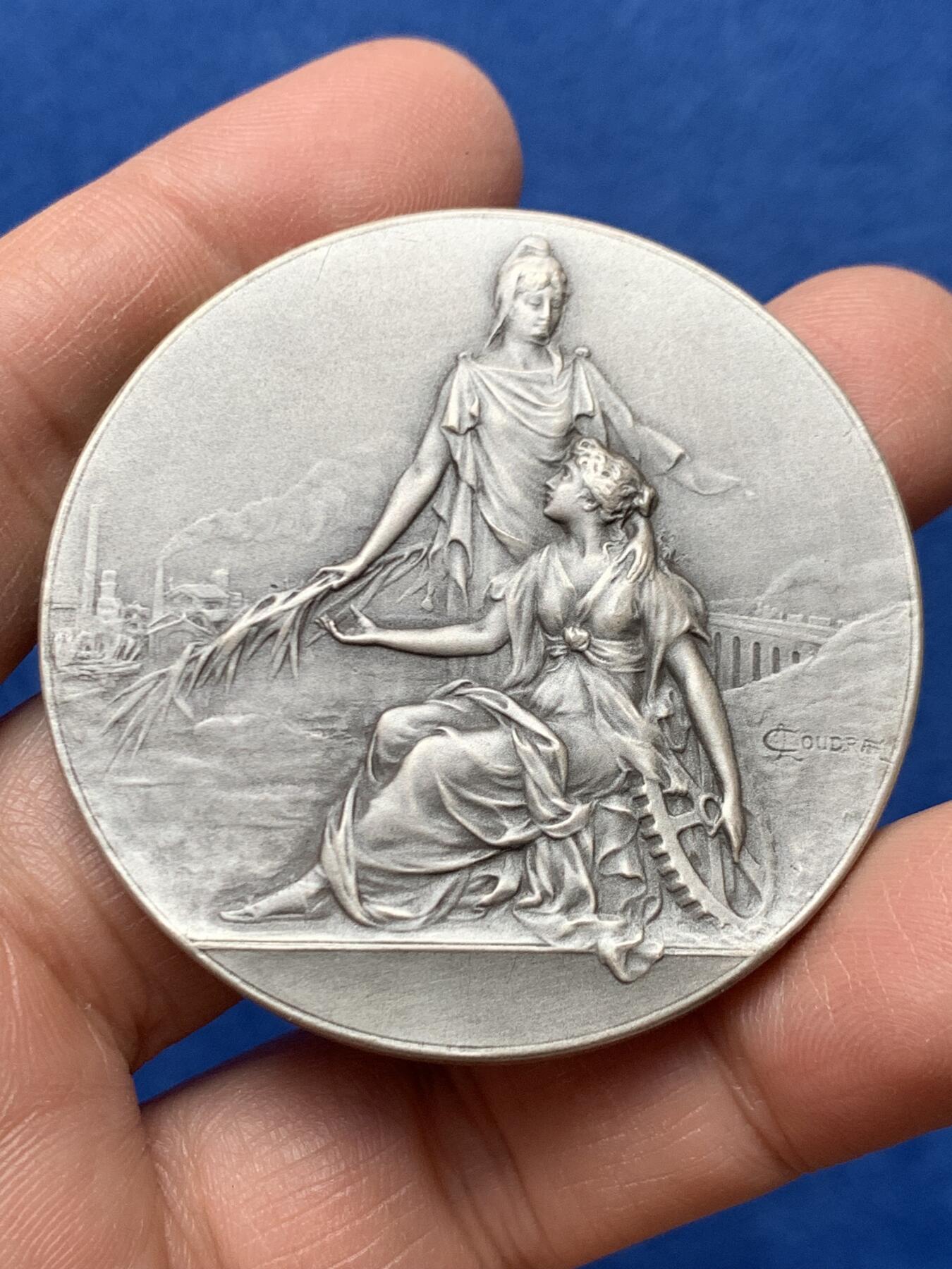 《竞宝斋》第460场 周日，周一，2场连拍 （全场包邮）欢迎送拍 法国1954年鲁昂市建筑业总工会镀银铜章，品相佳。直径50mm，重60.5g，丰饶角铜标。Coudray经典作品，刻画的是:玛丽安娜女神把棕榈枝送给抱着齿轮、代表着工业的女子，浪漫飘逸的新艺术风格作品。
