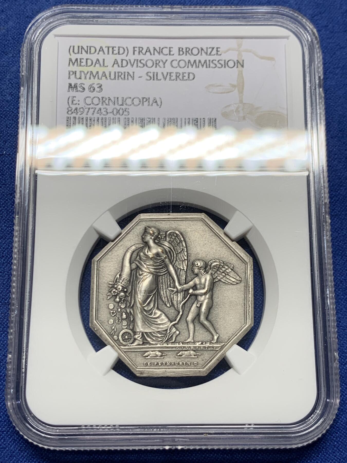 《竞宝斋》第460场 周日，周一，2场连拍 （全场包邮）欢迎送拍 NGC MS63 法国八角镀银铜质代币，正面雕刻一位羽翼女神(胜利或命运女神)牵引着小天使(爱神丘比特)，象征着命运引导下的爱与希望，左侧为撒落的丰收之角(Cornucopia)，右下角有艺术家名“DE PUYMAURIN”与雕刻标记，与整体构图共同形成寓言式场景。