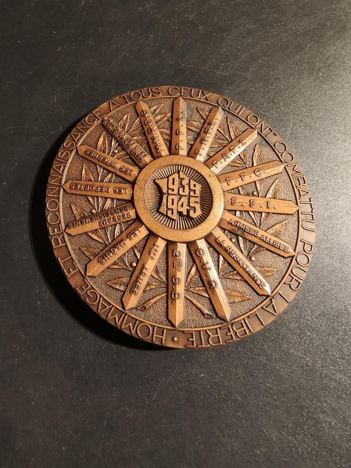 老王徽章第178期 法国1939-45战争大铜章    原盒    直径68mm    重量167.9g    该章放射状设计包含有特定的法国二战战功卓著的单位如:第10军、第2装甲师、FFI、自由法国运动等著名的抵抗组织