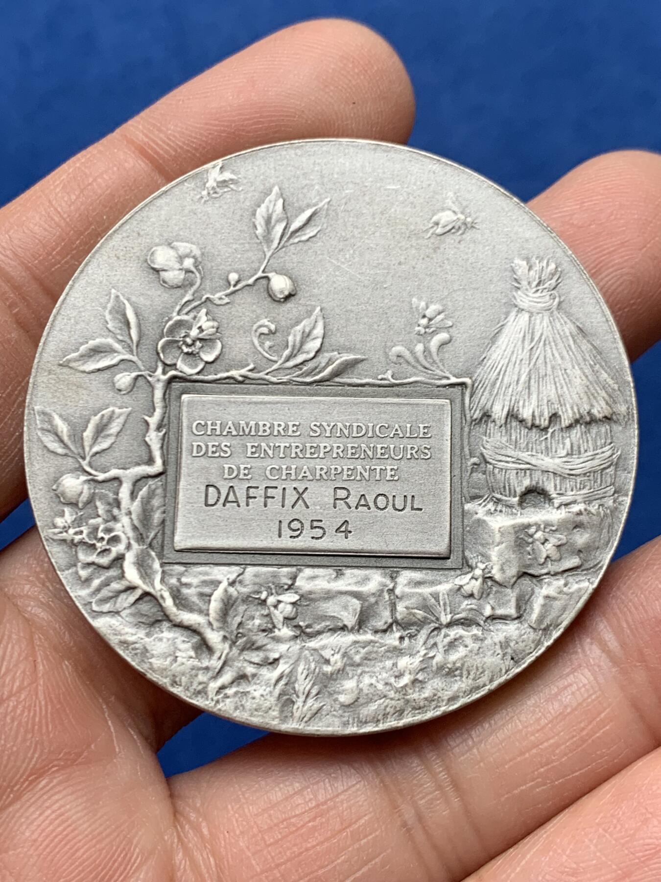 《竞宝斋》第460场 周日，周一，2场连拍 （全场包邮）欢迎送拍 法国1954年鲁昂市建筑业总工会镀银铜章，品相佳。直径50mm，重60.5g，丰饶角铜标。Coudray经典作品，刻画的是:玛丽安娜女神把棕榈枝送给抱着齿轮、代表着工业的女子，浪漫飘逸的新艺术风格作品。