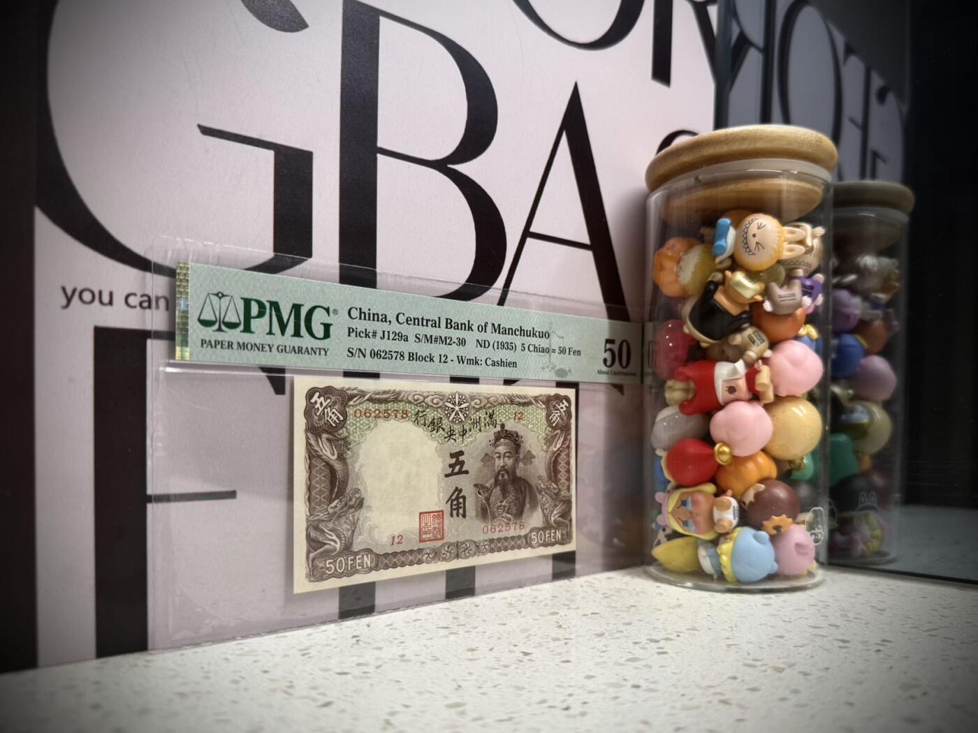 （自动截拍）PMG评级民国纸币专拍第20260126期，全场包邮 【乾奕收藏】出民国24年1935年满洲中央银行财神爷五角，早期乙号券版本背单线券，相比常见绿财神数量上更少，棕色财神图案，美国PMG50分