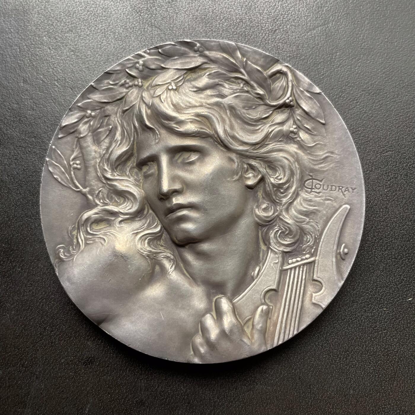 「木头集藏」章牌精品专场！ L.Coudray～法国音乐之神俄尔普斯大银章，直径：68 mm，162.3 g，边铭：丰饶角 ARGENT，名家高浮雕刻画作品，品相不错。俄耳甫斯，是古希腊神话中最著名的音乐家、诗人与先知，以超凡的音乐天赋和悲剧爱情闻名，太阳神阿波罗与缪斯女神卡利俄珀之子