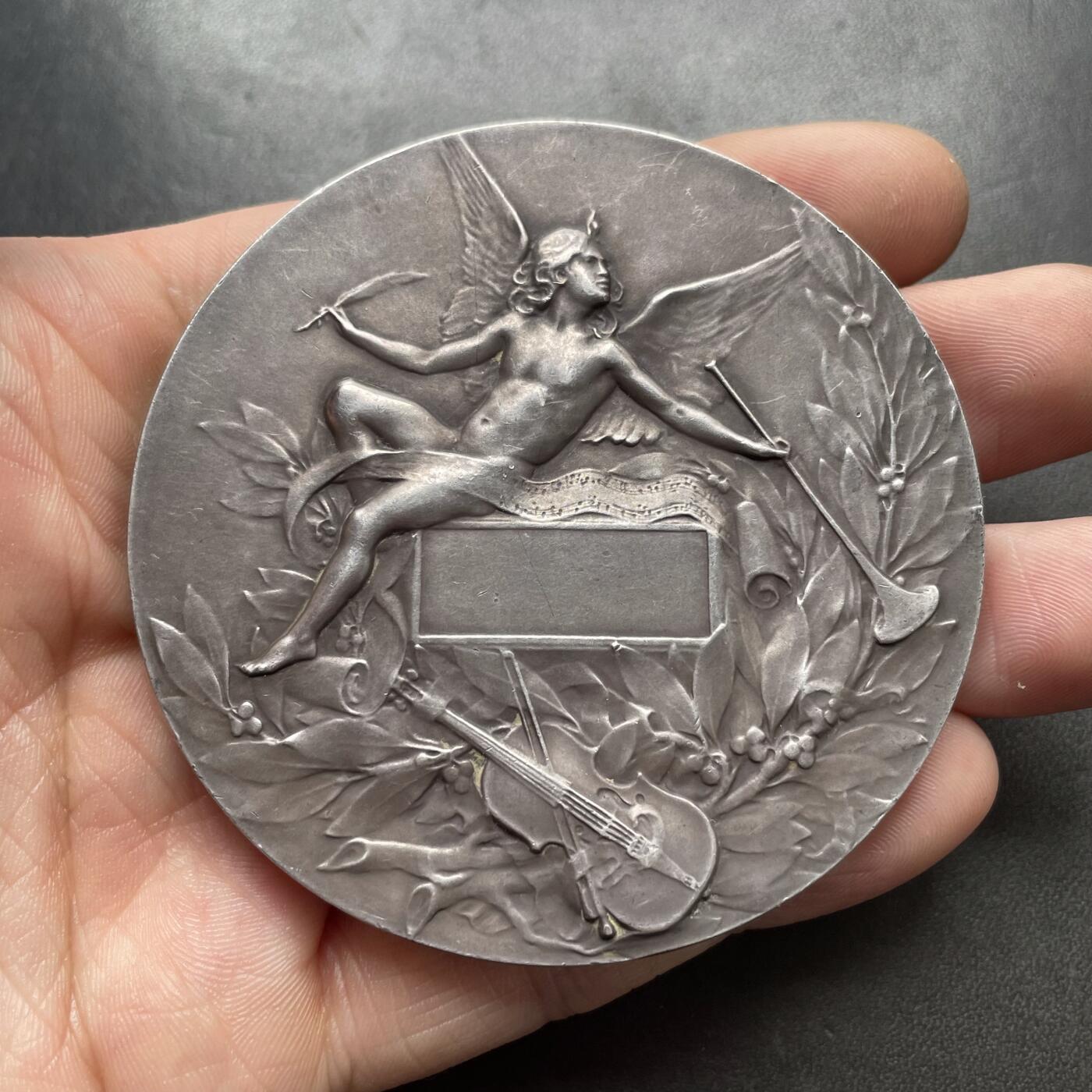 「木头集藏」章牌精品专场！ L.Coudray～法国音乐之神俄尔普斯大银章，直径：68 mm，162.3 g，边铭：丰饶角 ARGENT，名家高浮雕刻画作品，品相不错。俄耳甫斯，是古希腊神话中最著名的音乐家、诗人与先知，以超凡的音乐天赋和悲剧爱情闻名，太阳神阿波罗与缪斯女神卡利俄珀之子