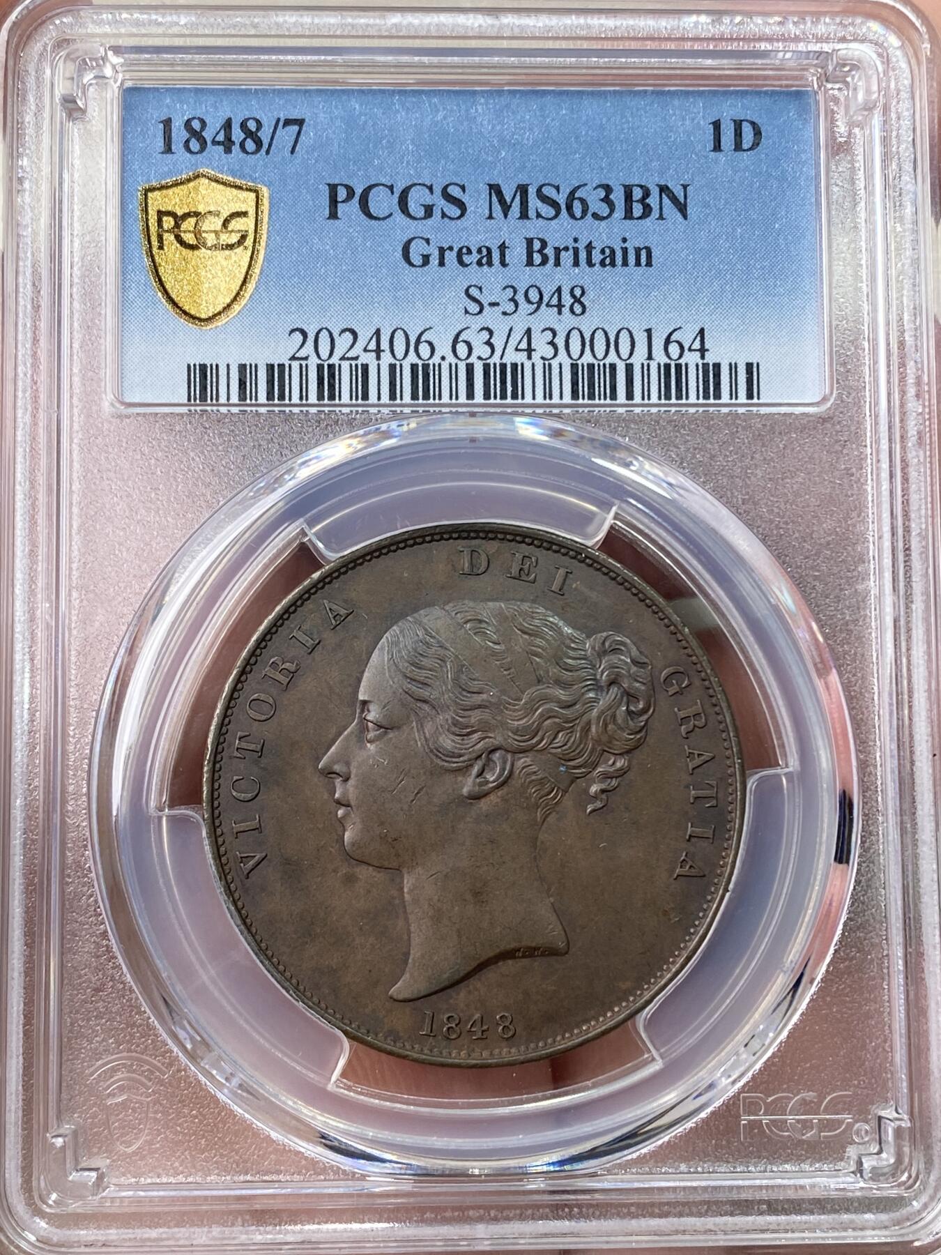 万国钱币拍卖第059期 PCGS MS63 1848/7年英国维多利亚便士 人见人爱的小维便士，早期用料很足，又大又厚，原铜色非常舒服。打制犀利高分好状态，大颗巧克力原生包浆醇厚。稀有的骑字版，市面很难见到。63分克劳斯目录价很久之前的参考价就是950美金，英系价格早已进阶。热门收藏潜力股，年轻可爱辫子头小维。