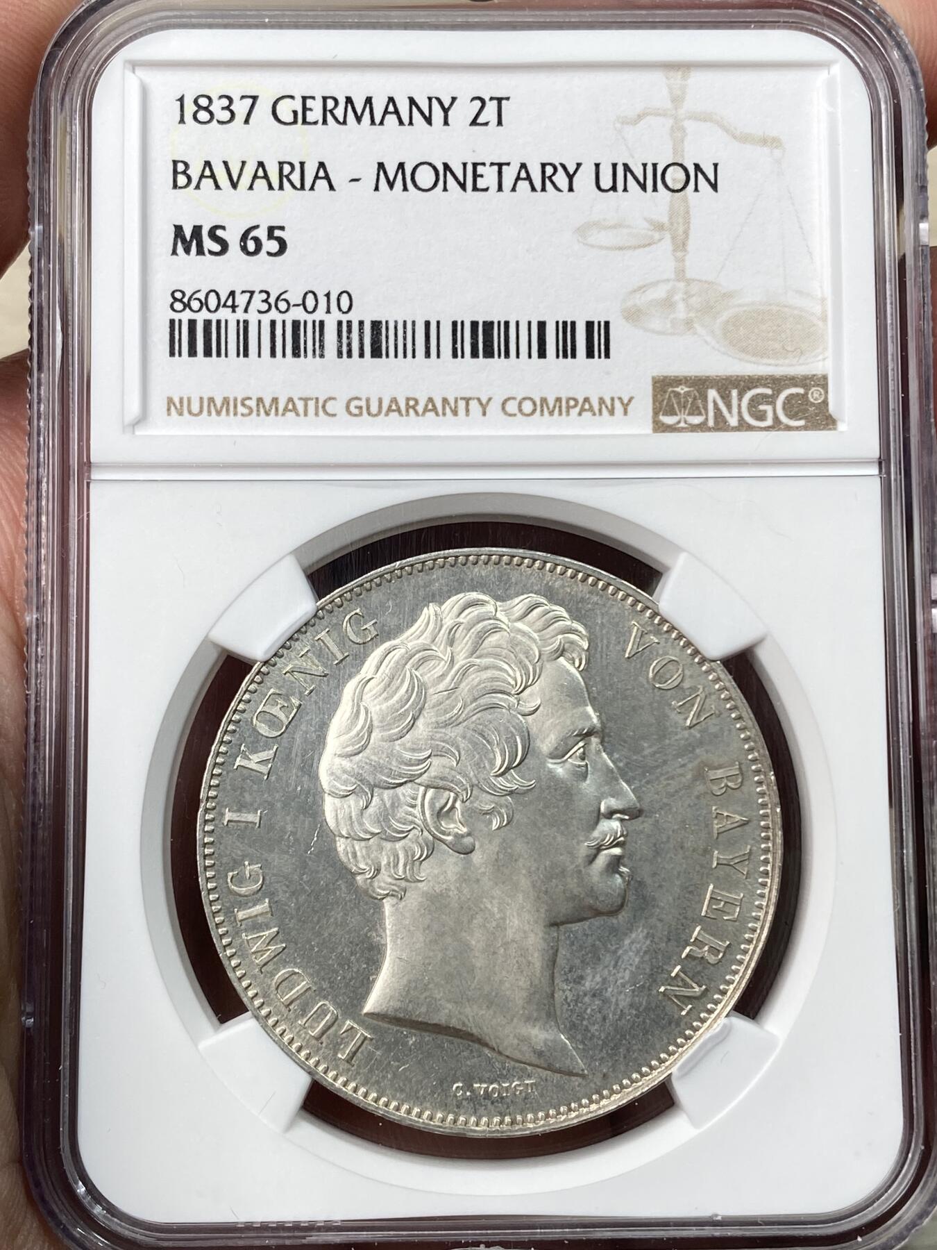 万国钱币拍卖第059期 NGC MS65 1837巴伐利亚路德维希一世货币联盟历史2泰勒 纪念1837年南德六邦在慕尼黑签署《慕尼黑货币协议》，决定停发王冠泰勒，转而以传统的古尔登为单位发行货币，2泰勒面值等于3.5古尔登，而此枚历史2t也就成为了邦国协议2泰勒的开山之作。 类镜面喷砂PL质感顶级BU状态 NGC唯一亚军分