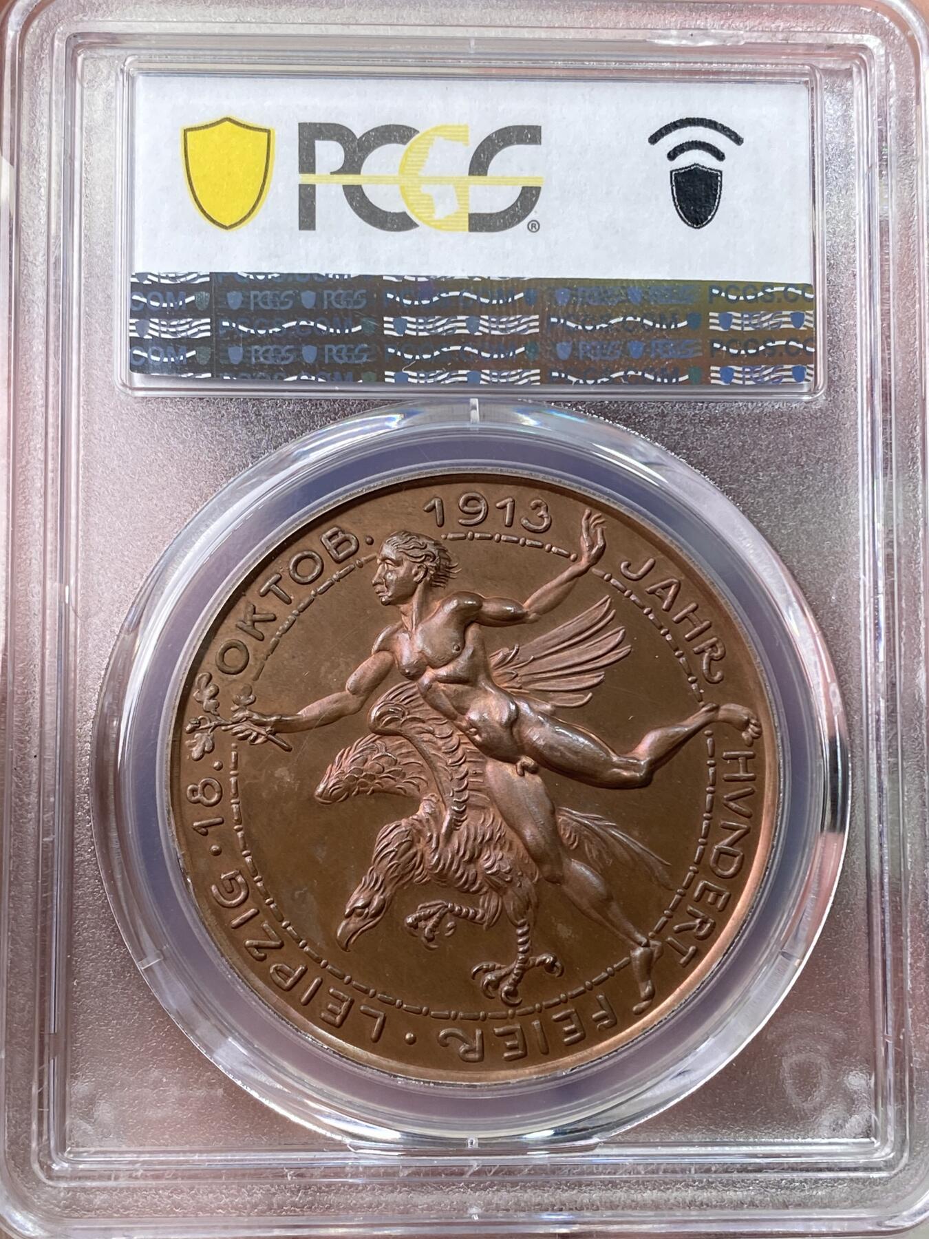 万国钱币拍卖第059期 PCGS SP64RB 1913年德国莱比锡战役百年纪念铜章 德章大神卡尔哥茨早期作品 40mm 唯一评级记录冠军分 罕见品种 高浮雕，精制工艺。丝滑底板拥有大量均匀的红棕色光泽，令人赏心悦目。设计极佳，精美绝伦。正面:德皇威廉二世身着铠甲半身像，手持宝剑与权杖，左侧有罕见的作者KG签名缩写。背面:裸体青年手持橡树叶，飞翔的德意志雄鹰伴其左右。莱比锡战役，又称民族会战。拿破仑惨败，被迫返回法国。