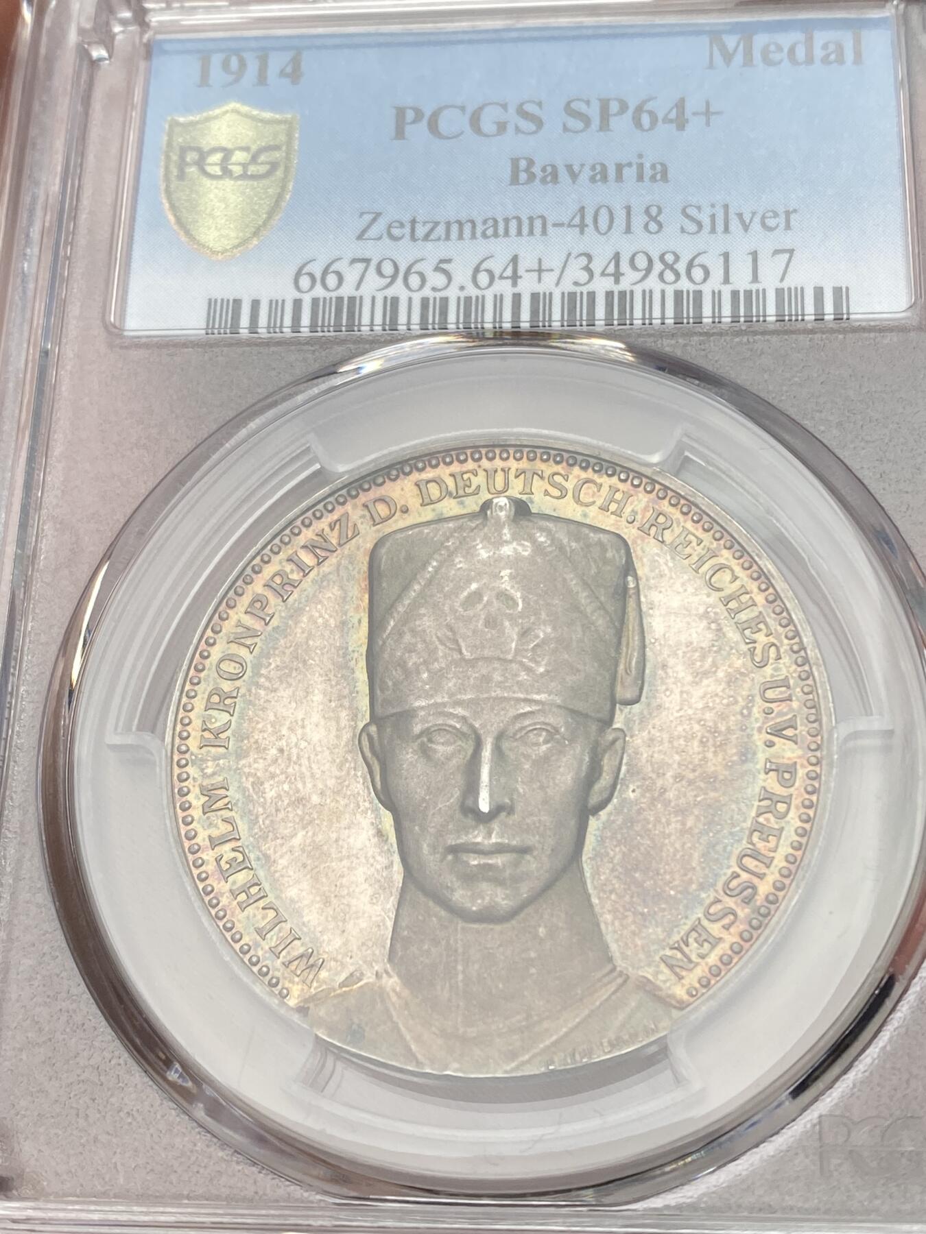 万国钱币拍卖第059期 PCGS SP64+ 1914年德国一战银章 威廉王储/隆维战役 冠军分唯一记录 官网广告封面章 银章评级给+号极为不易，顶级状态。高浮雕，精制底板。紫罗兰浓郁彩虹包浆，绚丽光泽，冰霜图案，微妙的色彩融合极具魅力。正面:威廉王储半身像，身穿骷髅骠骑兵制服。背面:手持帝国鹰徽盾牌和长剑的武士，骑兵在战场上无畏的冲锋。作为威廉皇帝的继承人，他是德意志帝国和普鲁士王国的最后一位王储，直至君主制废除。
