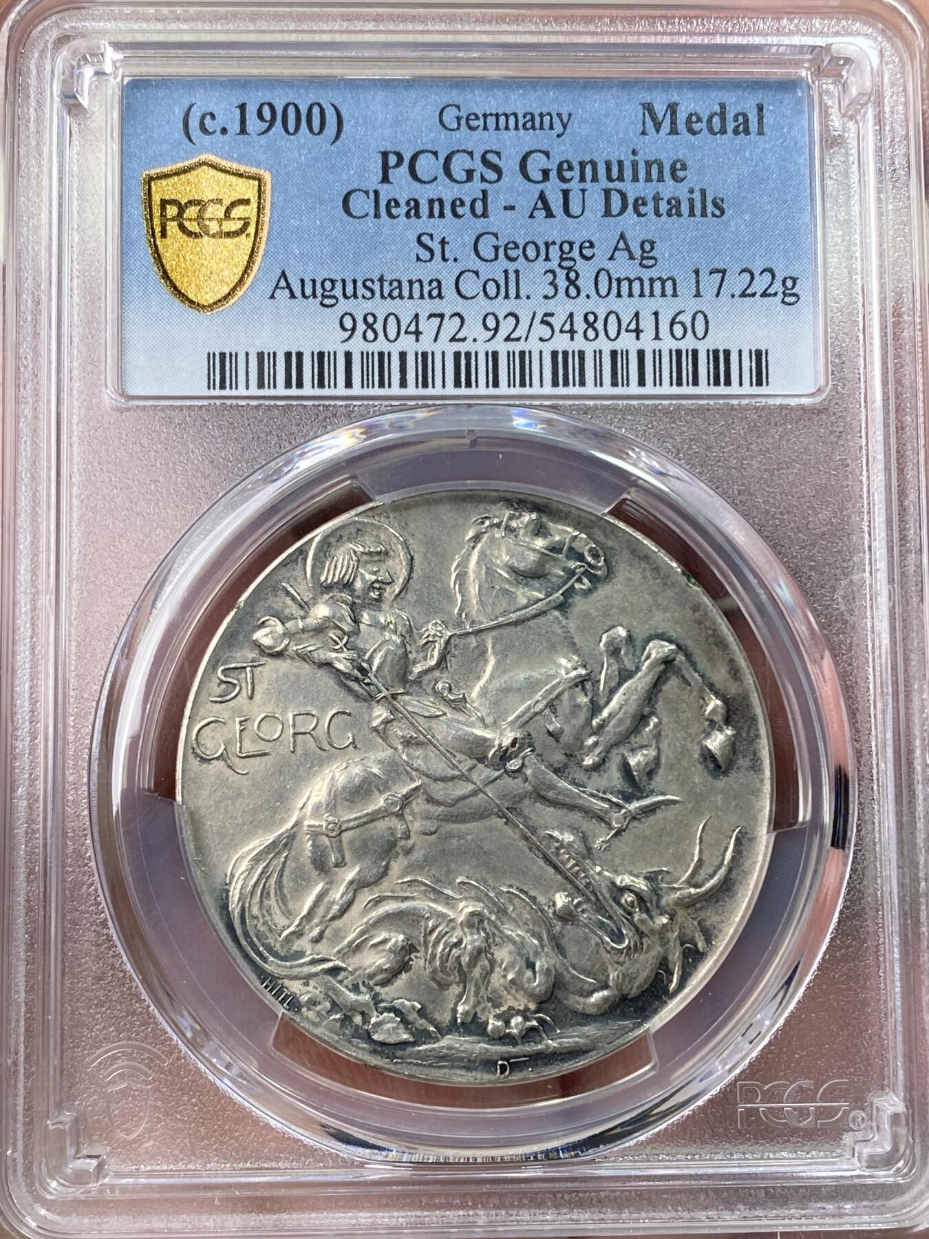 万国钱币拍卖第059期 PCGS AUD 1900年左右德国圣乔治幸运符银章 PC唯一评级记录 极稀品种 浮雕精铸，设计极佳，古典与现代的结合。画面空间张力十足，实物非常漂亮。名家旧藏。正面:德意志化的圣乔治骑士骑马手执长枪插入魔龙的口中。魔龙并非传统的西方魔龙形象，而且典型的中国龙。当时正值义和团运动，以及八国联军侵华。极其少见的设计，结合了宗教和历史事件。背面:耶稣在船上。拉丁铭文意为风暴中的安全。