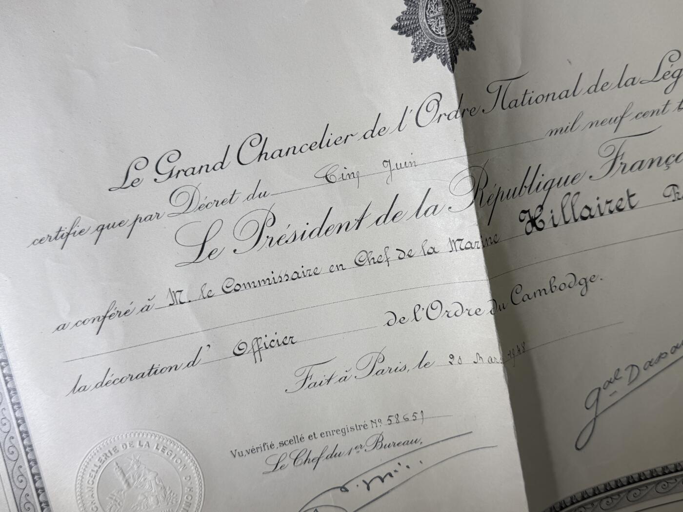 戎马世界章牌大赏第110期 法属柬埔寨王国军官级王冠勋章证书，有折痕破损，属于法国海军专员，有得主相关履历，得主1939年晋升为首席专员，曾在远东的“雷居勒斯号”巡洋舰服役，随后登上“恩特卡斯特奥号”驱逐舰与“巴黎号”战列舰，在“圣女贞德号”巡洋舰度过两年时光后，他曾短暂负责学员晋升考核