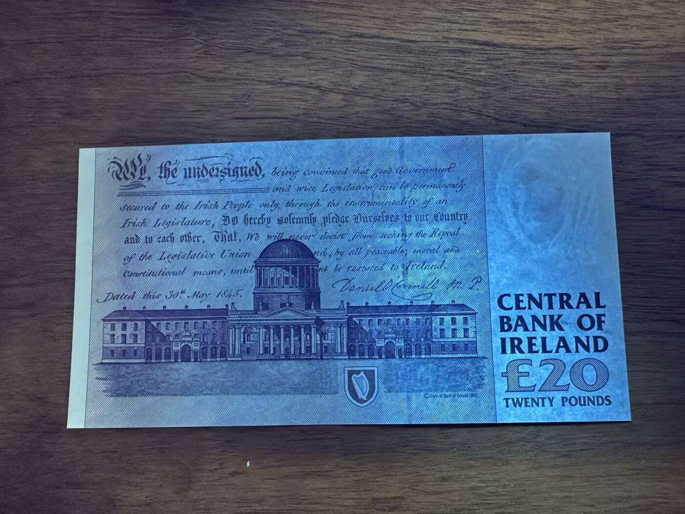 徐霞客拍卖首拍 	爱尔兰	P-77b 1999年20镑	MRV763520 unc-	纸币正面背景是奥康奈尔的故乡——凯里郡的Derrynane House（现Derrynane Abbey），建筑细节中暗藏“£20”微缩文字防伪；背面则是都柏林的四法院（Four Courts），这座建筑不仅是爱尔兰最高法院所在地，其墙面上的弹孔更是1916年复活节起义的历史印记。