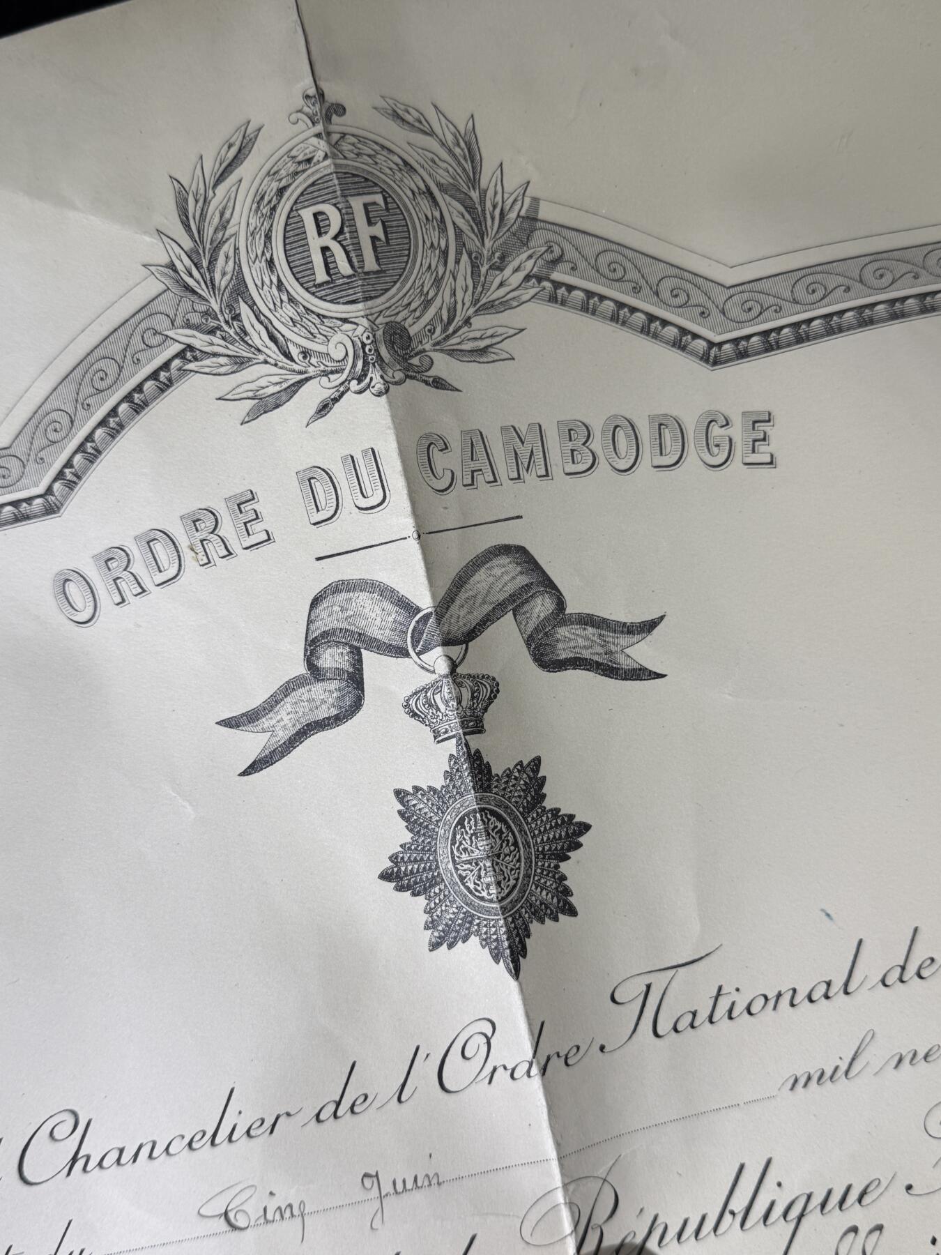 戎马世界章牌大赏第110期 法属柬埔寨王国军官级王冠勋章证书，有折痕破损，属于法国海军专员，有得主相关履历，得主1939年晋升为首席专员，曾在远东的“雷居勒斯号”巡洋舰服役，随后登上“恩特卡斯特奥号”驱逐舰与“巴黎号”战列舰，在“圣女贞德号”巡洋舰度过两年时光后，他曾短暂负责学员晋升考核