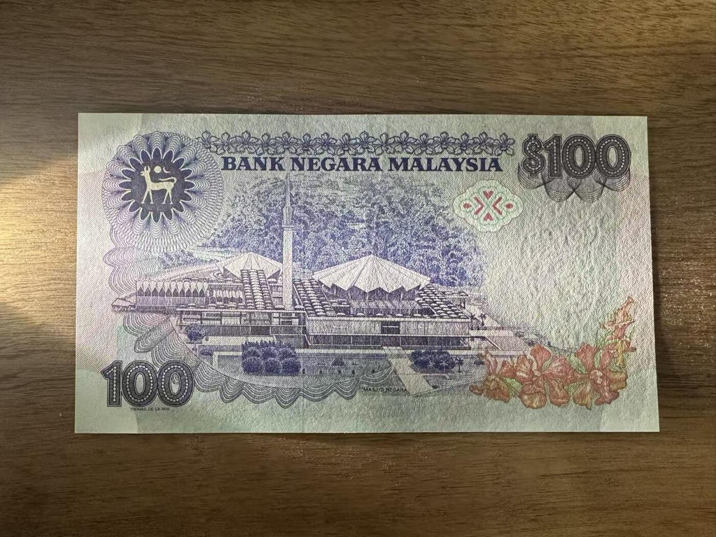 徐霞客拍卖首拍 马来西亚	P-24 1983-84年100元	ZB0753159	unc- 主图为端古·阿卜杜勒·拉赫曼的官方肖像，周围环绕着马来西亚传统花卉纹样与几何装饰，融合了马来文化的精致美学。背面以马来西亚现代化建设成就为主题，通常包含港口、工业区等图案，直观展现了当时经济高速发展的面貌