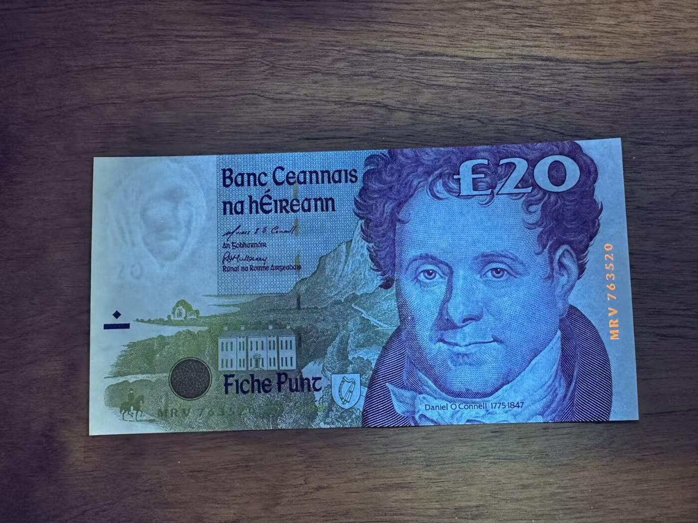 徐霞客拍卖首拍 	爱尔兰	P-77b 1999年20镑	MRV763520 unc-	纸币正面背景是奥康奈尔的故乡——凯里郡的Derrynane House（现Derrynane Abbey），建筑细节中暗藏“£20”微缩文字防伪；背面则是都柏林的四法院（Four Courts），这座建筑不仅是爱尔兰最高法院所在地，其墙面上的弹孔更是1916年复活节起义的历史印记。