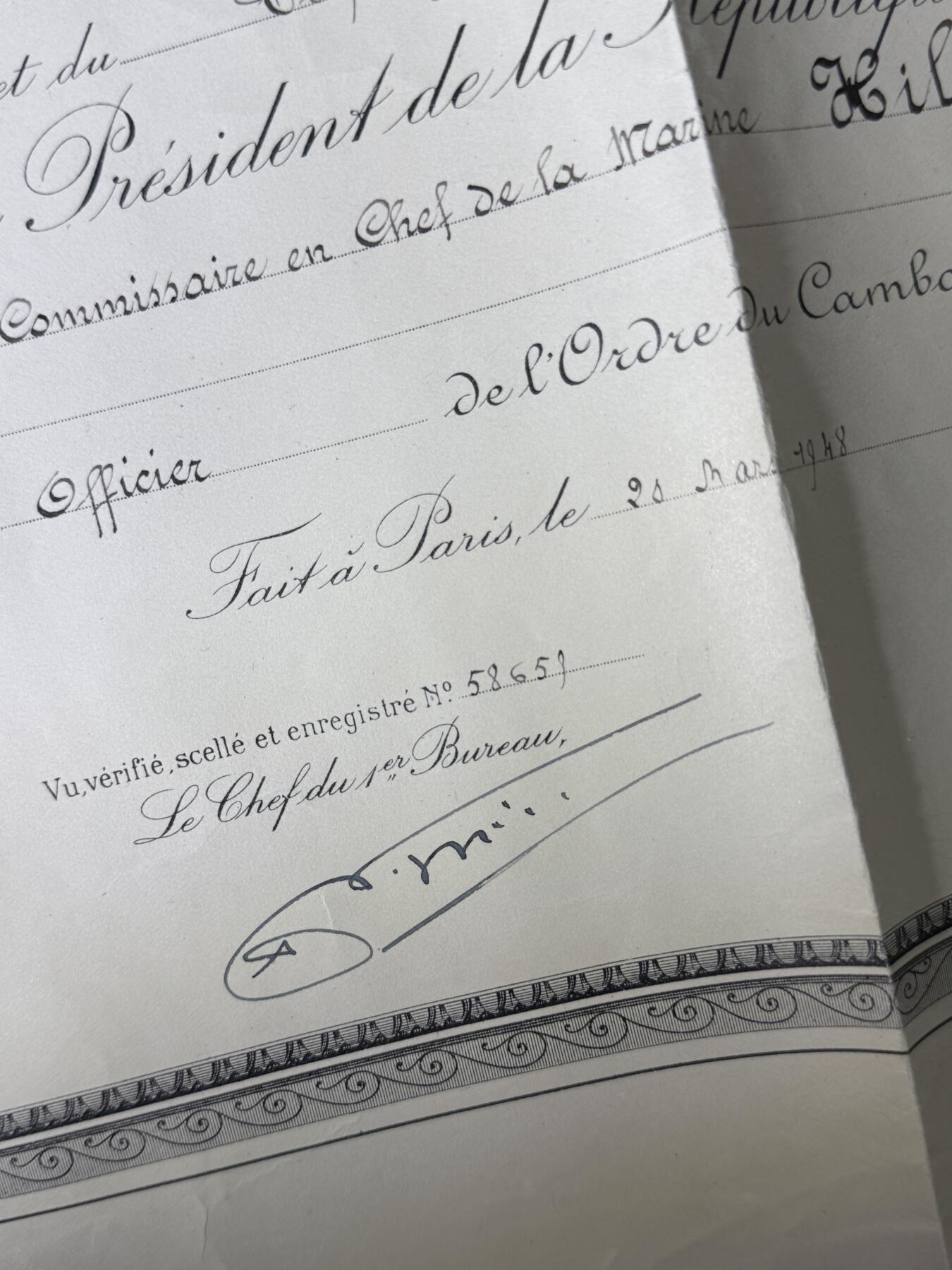 戎马世界章牌大赏第110期 法属柬埔寨王国军官级王冠勋章证书，有折痕破损，属于法国海军专员，有得主相关履历，得主1939年晋升为首席专员，曾在远东的“雷居勒斯号”巡洋舰服役，随后登上“恩特卡斯特奥号”驱逐舰与“巴黎号”战列舰，在“圣女贞德号”巡洋舰度过两年时光后，他曾短暂负责学员晋升考核