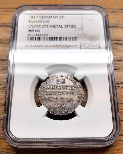 凡希社世界钱币微拍第三百十九期 - 1817德国法兰克福宗教改革300周年银质试铸样币NGC-MS61，珍稀品种。正面铭文意为“宗教改革第三次庆典 1817”，边缘环绕“UNSER GOTT IST EINE FESTE BURG”（我们的上帝是坚固的堡垒），这句源自马丁·路德的赞美诗，是宗教改革的标志性口号。