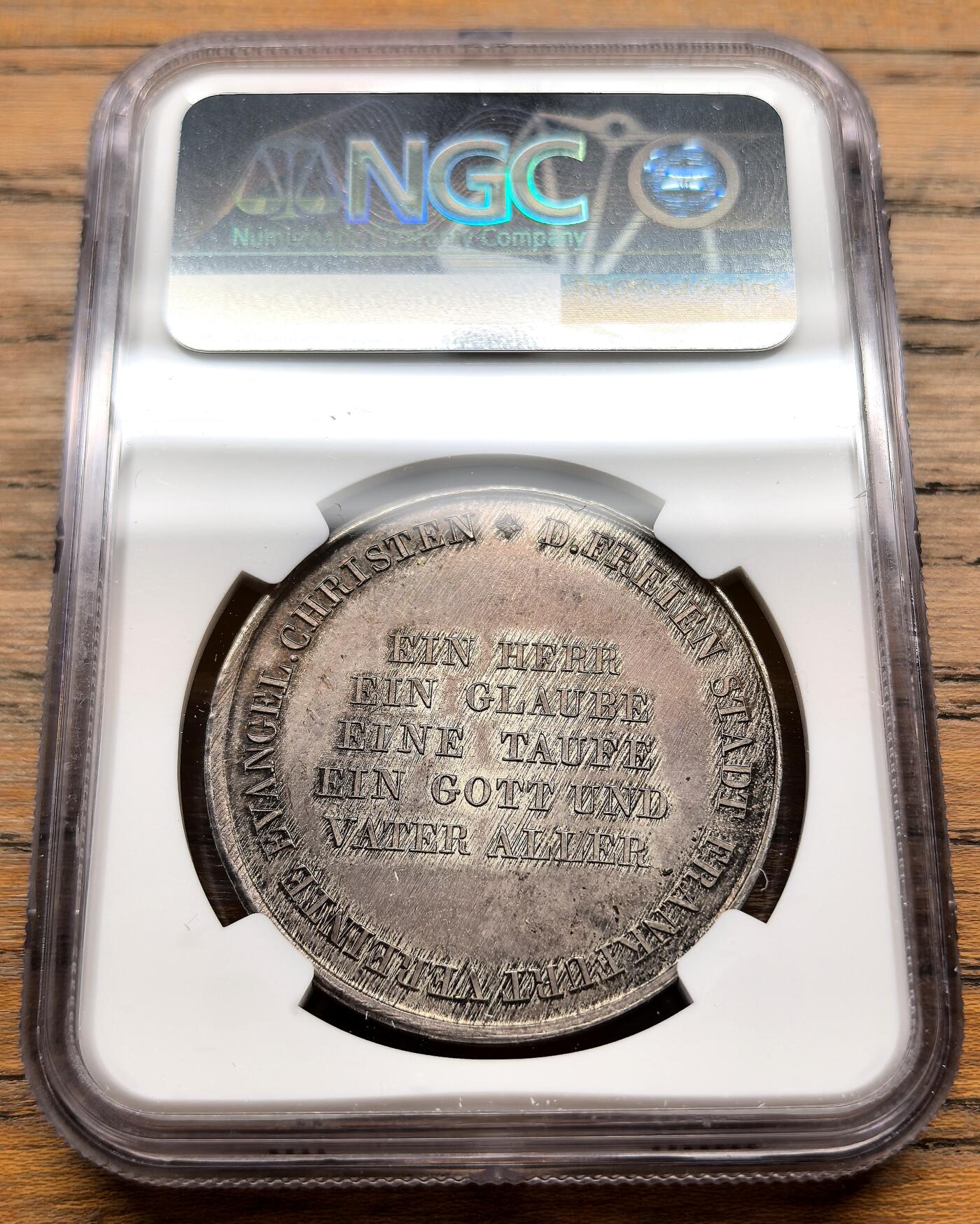凡希社世界钱币微拍第三百十九期 1817德国法兰克福宗教改革300周年纪念泰勒型银质币章NGC-MS63，该系列的大规格更为罕见，背面中央铭文为“EIN HERR, EIN GLAUBE, EINE TAUFE, EIN GOTT UND VATER ALLER”，源自《圣经·以弗所书》，意为“一主、一信、一洗、一神，就是众人的父”，体现了新教的核心教义。