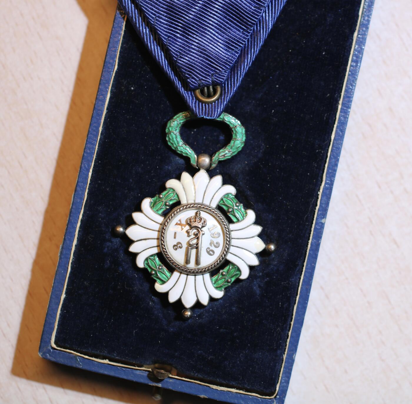 大猫徽章拍卖 第287期 南斯拉夫皇冠勋章，四级，带原装盒。勋章珐琅工艺精美，无缺损。盒身覆以蓝色皮革，盒盖上饰有金色字样。盒内衬以天鹅绒和缎面。白色盒盖上印有瑞士制造商“Huguenin Freres & Co.”的标记，一处为法语，另一处为南斯拉夫语译文。绶带略有撕裂。整套勋章品质上乘，保存完好，虽有岁月痕迹，但仍不失韵味。珐琅局部有修复