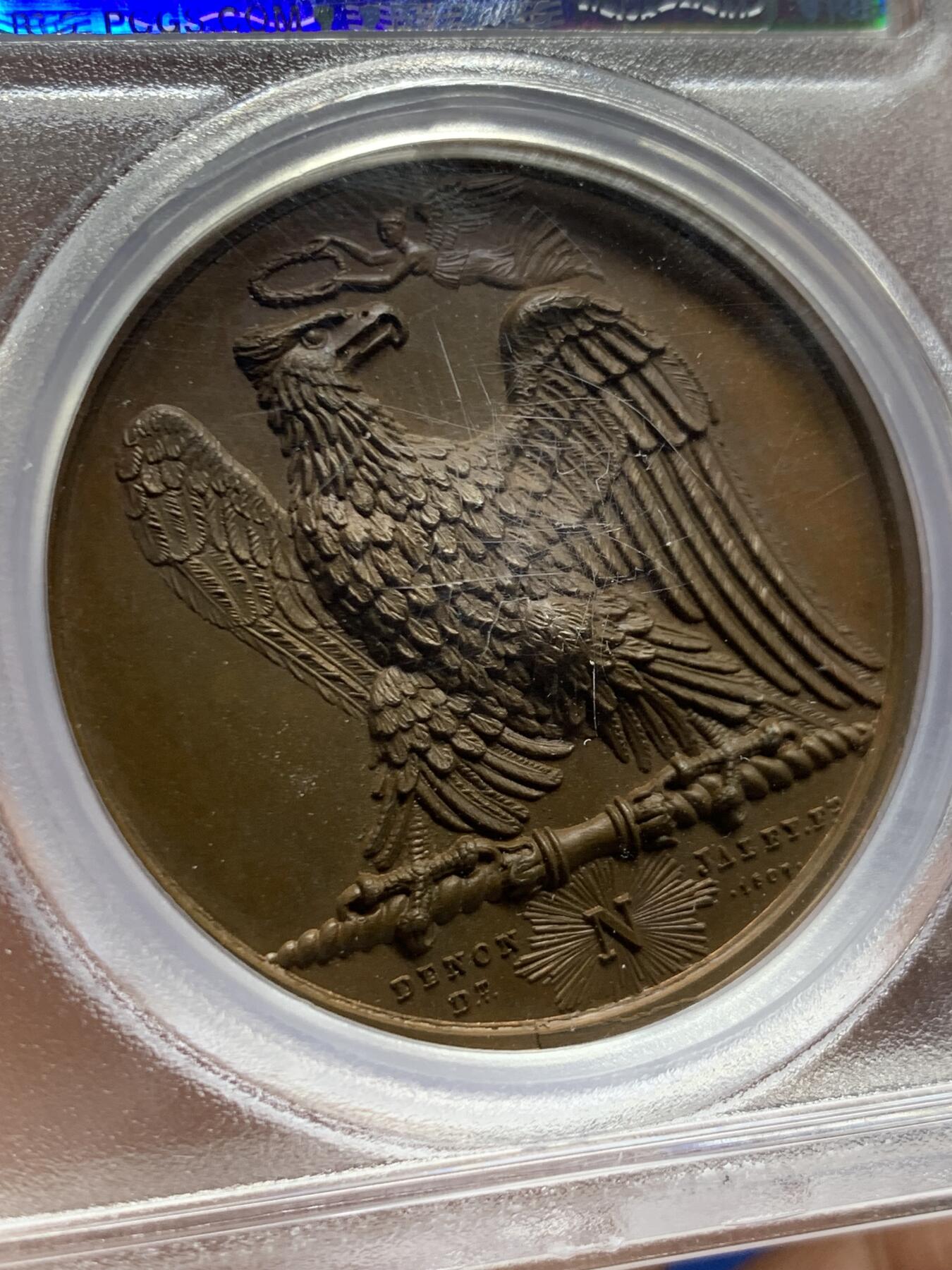 《竞宝斋》第461场 周日，周一，2场连拍 （全场包邮）欢迎送拍 PCGS SP65 冠军分！法国1807年拿破仑一世年度胜利原铸铜章 巴黎造币厂 巧克力包浆 帝国之鹰展翅爪子锋利 紧紧攥住矗立于N记雷电权杖之上 目光锐利如炬 羽翼丰满 丝缕清晰细节感人 作为拿皇的拟人化象征 接受上空胜利女神飞舞空中送来月桂花环为其加冕 作为年度总结庆祝过去的一年中军队获取的胜利 稀少珍贵品种 加厚盒