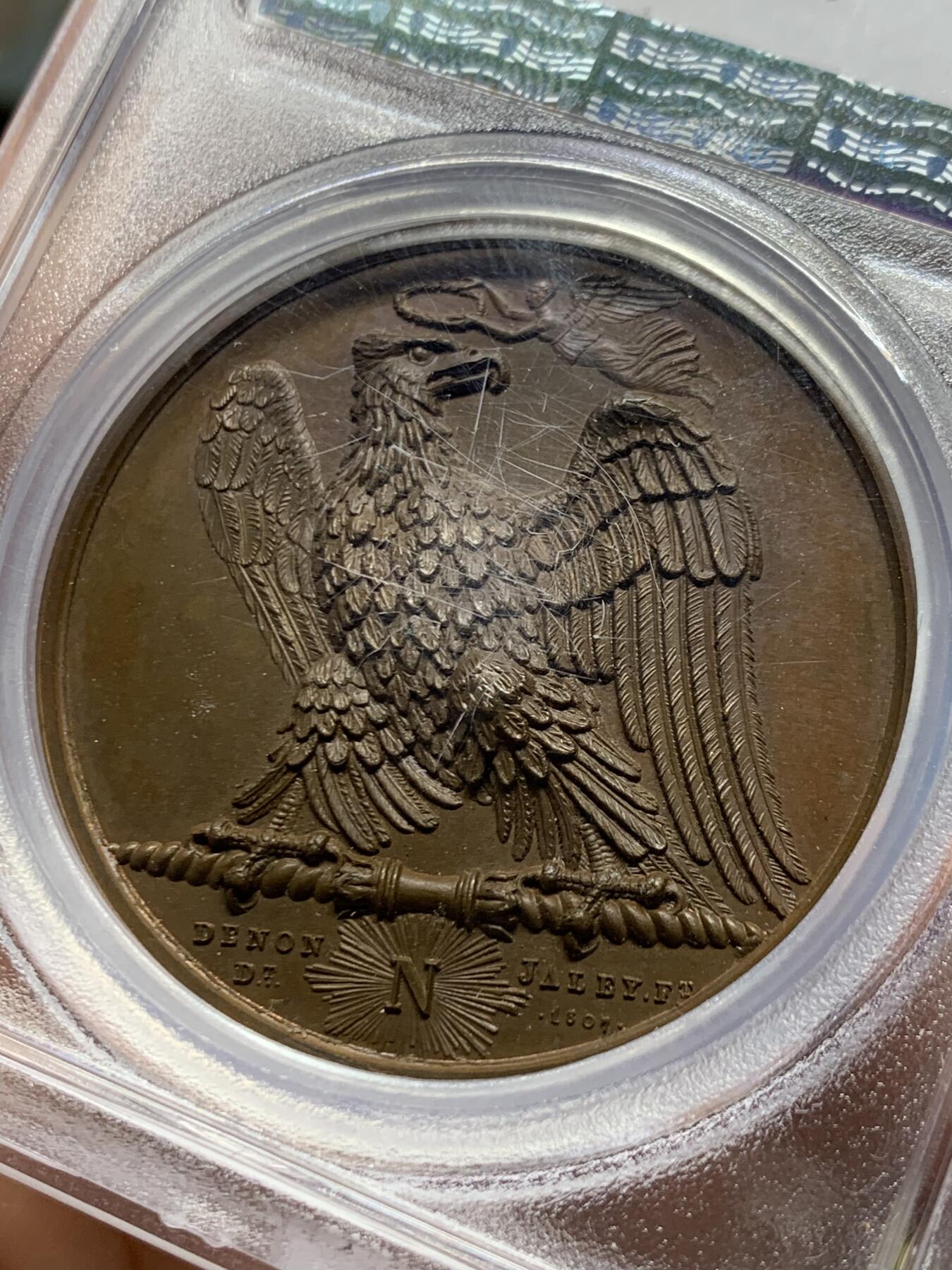 《竞宝斋》第461场 周日，周一，2场连拍 （全场包邮）欢迎送拍 PCGS SP65 冠军分！法国1807年拿破仑一世年度胜利原铸铜章 巴黎造币厂 巧克力包浆 帝国之鹰展翅爪子锋利 紧紧攥住矗立于N记雷电权杖之上 目光锐利如炬 羽翼丰满 丝缕清晰细节感人 作为拿皇的拟人化象征 接受上空胜利女神飞舞空中送来月桂花环为其加冕 作为年度总结庆祝过去的一年中军队获取的胜利 稀少珍贵品种 加厚盒