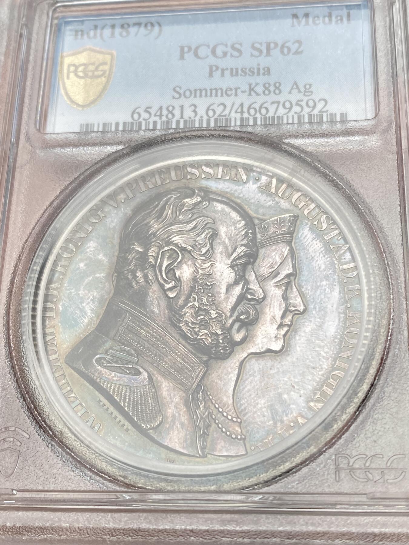 万国钱币拍卖第059期 PCGS SP62  1879年德国普鲁士威廉一世金婚纪念大银章 PC亚军分 双面均为著名普鲁士宫廷模刻师弗里德里希威廉库尔里希(F.W.Kullrich)刻制。 背面中央清晰刻有七行宗教寓意铭文，摘自《罗马书》第12章第12节：要喜乐于盼望，忍耐于患难，祷告里恒切；发行情况：1879年配套赠送给贵宾，1881年以后正式对外发型。