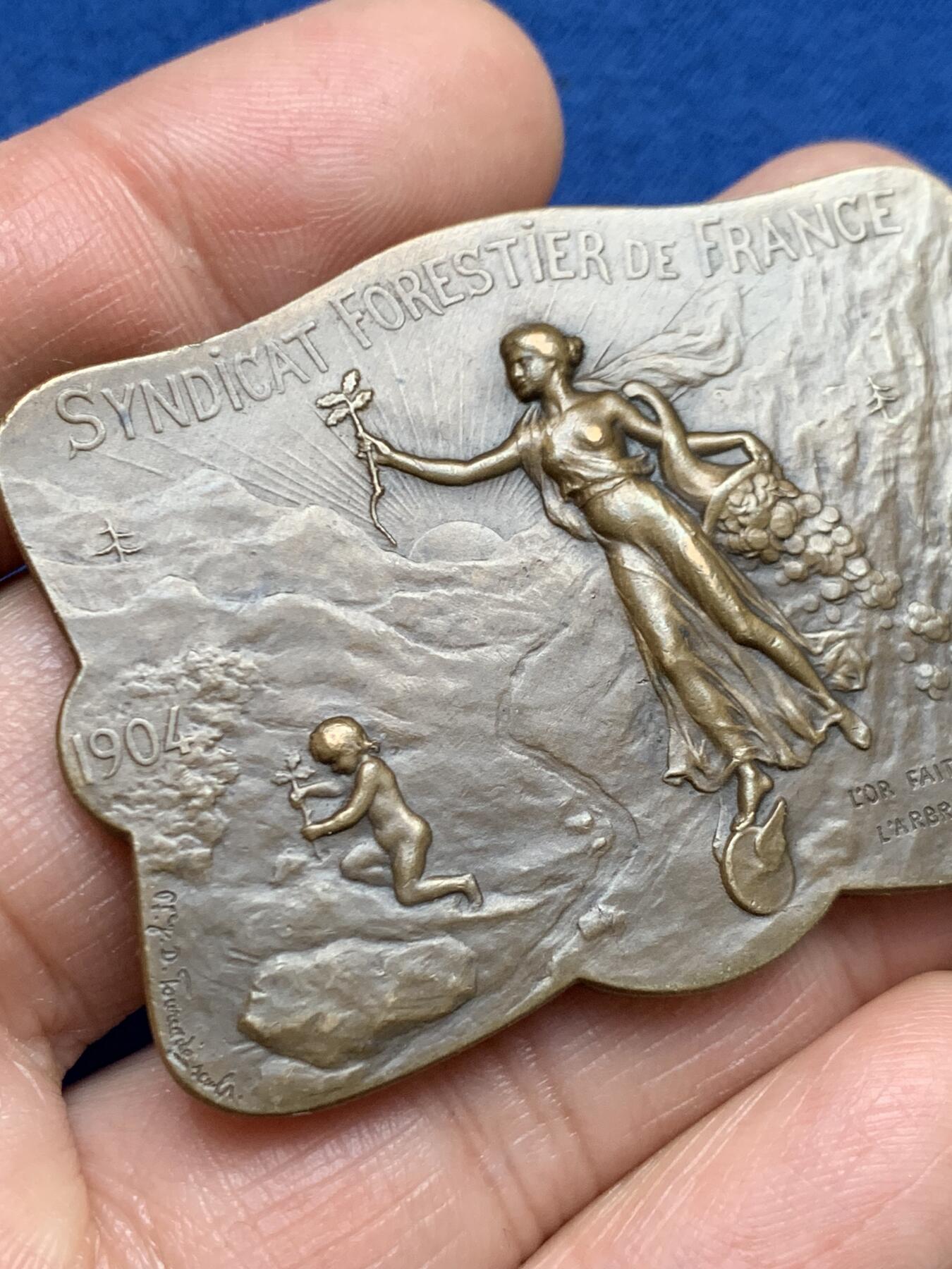 《竞宝斋》第461场 周日，周一，2场连拍 （全场包邮）欢迎送拍 法国1907林业联盟协会铜制异形奖章，首见款。正面：春之女神右手挽鲜花，左手播种树苗，脚踏风火轮，底部一个小天使在种植树苗。直径：53.6mm*40.8mm，重：38.2g，丰饶角铜标。