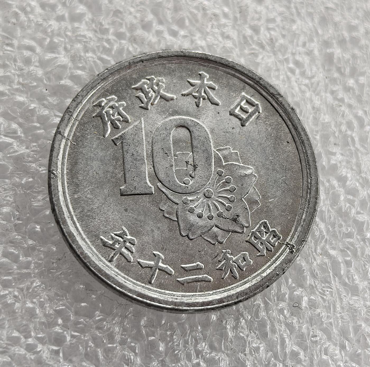 外国优质老铜币高银银币，周六九点倒数截拍，满百包邮，持续收拍 极美品昭和二十一年（1946 年）日本十钱铝币，正面 “日本政府”“昭和二十一年”、数字 10 与樱花，背面皇室菊纹、稻穗与 “十钱”。二战后日本金属匮乏改用铝铸，稻穗象征农业，是战后初期经济重建与货币改革的实物见证。