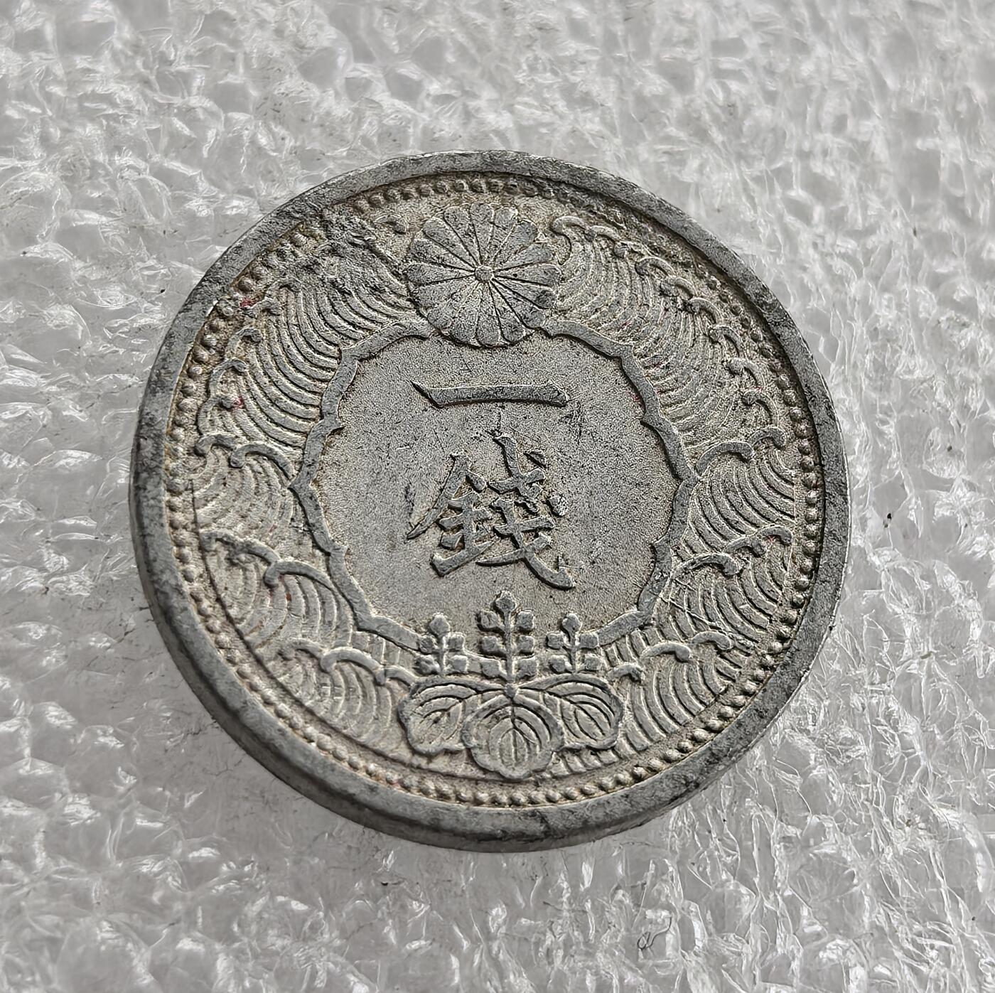 外国优质老铜币高银银币，周六九点倒数截拍，满百包邮，持续收拍 昭和十五年（1940 年）日本一钱铝币，正面皇室菊纹、海浪纹配 “一钱”，彰显皇权与海洋意象；背面 “大日本 昭和十五年”、飞鸟与樱花纹。二战时期日本金属匮乏改用铝铸，是战时经济与军国主义扩张的货币实物见证。