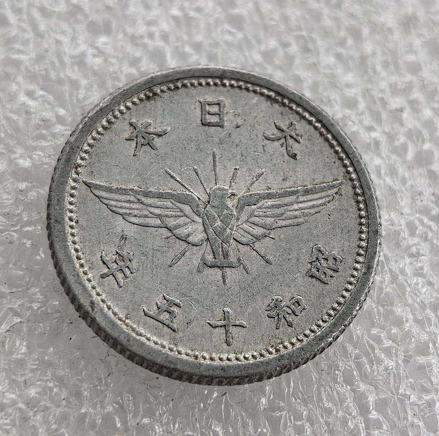 外国优质老铜币高银银币，周六九点倒数截拍，满百包邮，持续收拍 昭和十五年（1940 年）日本五钱铝币，正面 “大日本 昭和十五年” 配飞鸟纹（军国主义象征），背面 “五钱”、皇室菊纹与祥云。二战时期日本金属匮乏改用铝铸，是战时经济与军国主义扩张的货币实物见证。