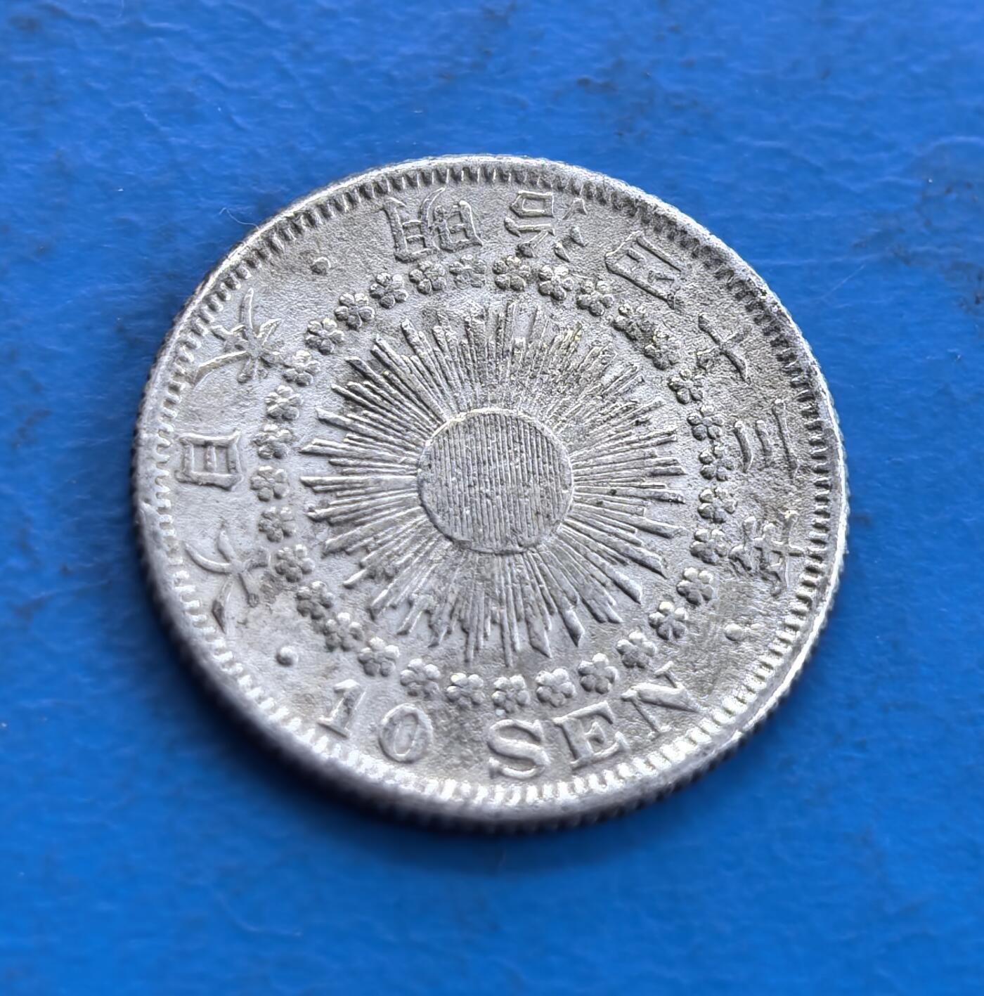 外国优质老铜币高银银币，周六九点倒数截拍，满百包邮，持续收拍 日本明治四十三年十钱银币，正面 “十钱” 居中，上置菊纹章，桐叶樱花枝环绕，枝叶雕工细腻；背面旭日光芒璀璨，纪年与 “10 SEN” 环绕，小花点缀，纹饰对称规整，银质温润，尽显日式钱币美学。