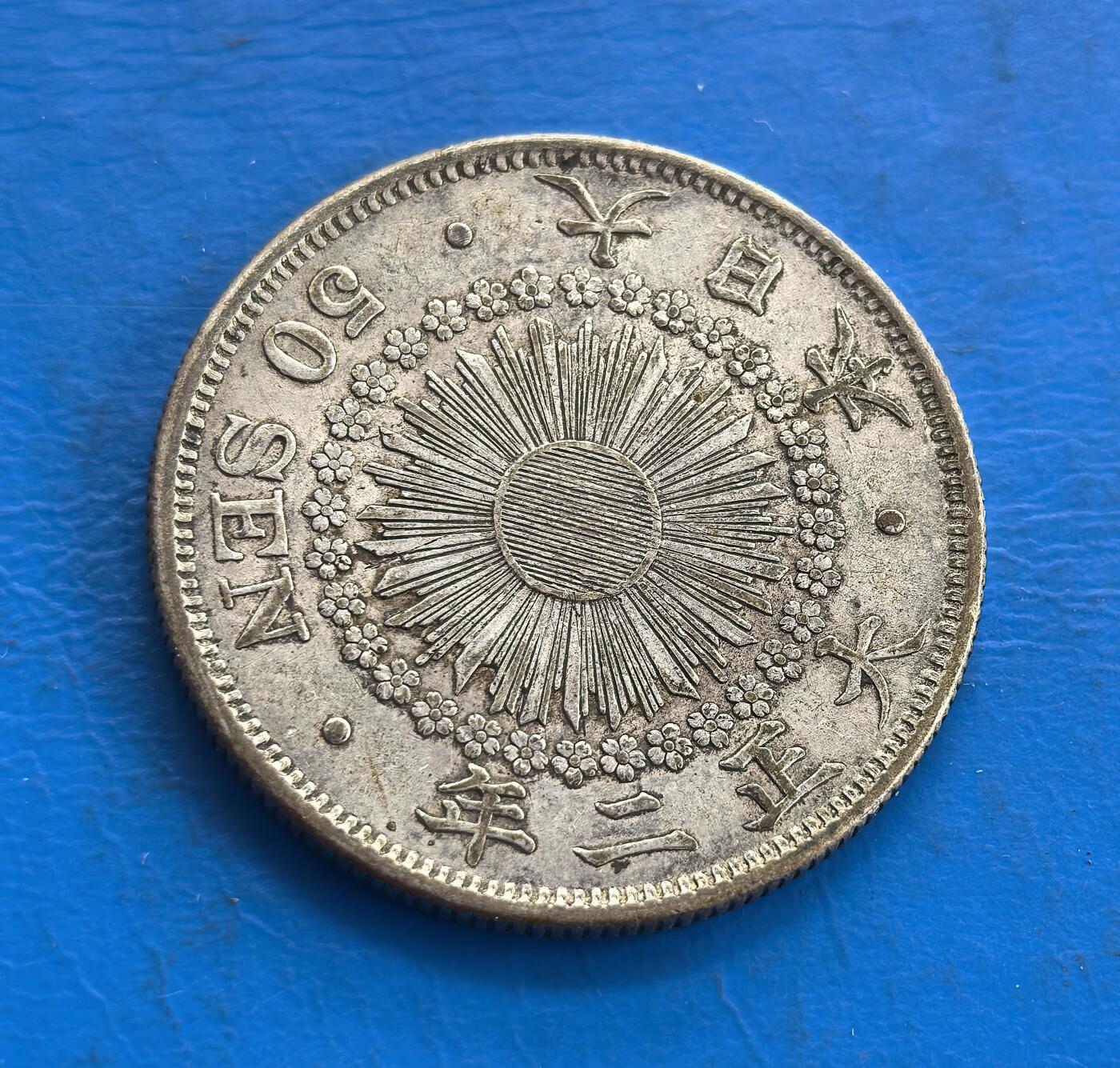 外国优质老铜币高银银币，周六九点倒数截拍，满百包邮，持续收拍 日本大正二年（1913 年）五十钱银币，正面以 “五十钱” 为核心，环绕桐叶、菊花纹与蝴蝶结，尽显日式典雅；背面是放射状旭日纹，搭配 “50 SEN” 与纪年，象征明治维新后的国运升腾，兼具历史与工艺价值。