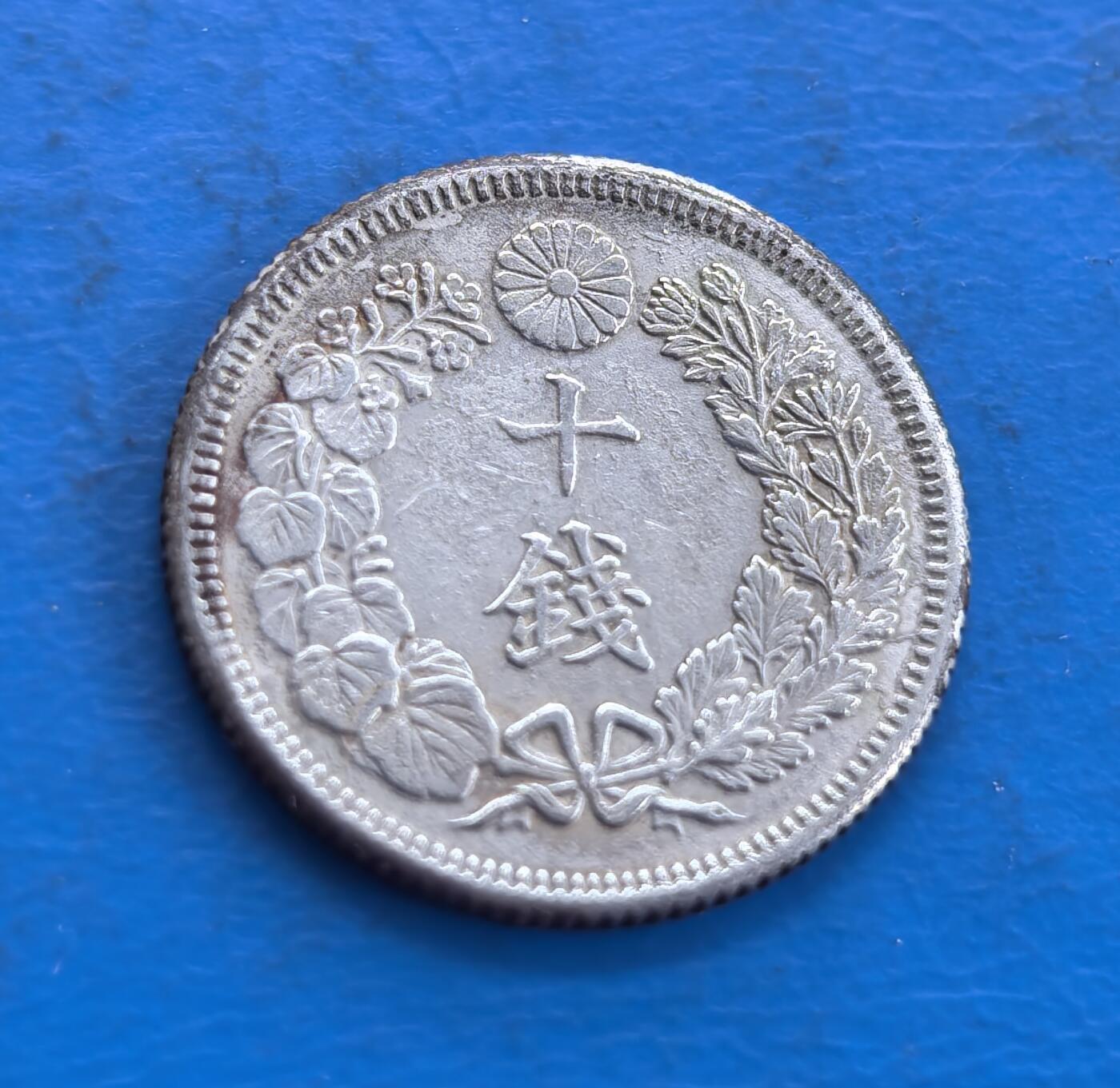 外国优质老铜币高银银币，周六九点倒数截拍，满百包邮，持续收拍 日本大正五年十钱银币，正面 “十钱” 居中，上置菊纹章，桐叶樱花枝环绕，枝叶雕工细腻，蝴蝶结纹饰精巧；背面旭日光芒璀璨，小花点缀，纹饰对称规整，银质温润，尽显日式钱币美学。
