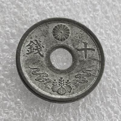 外国优质老铜币高银银币，周六九点倒数截拍，满百包邮，持续收拍 - 极美品昭和十九年（1944 年）日本十钱锡币，正面皇室菊纹、桐叶祥云纹彰显皇权与传统，圆孔形制节省材料；背面 “大日本”“昭和十九年” 标注国名年号，是二战末期日本金属匮乏、战时经济崩溃的货币见证。
