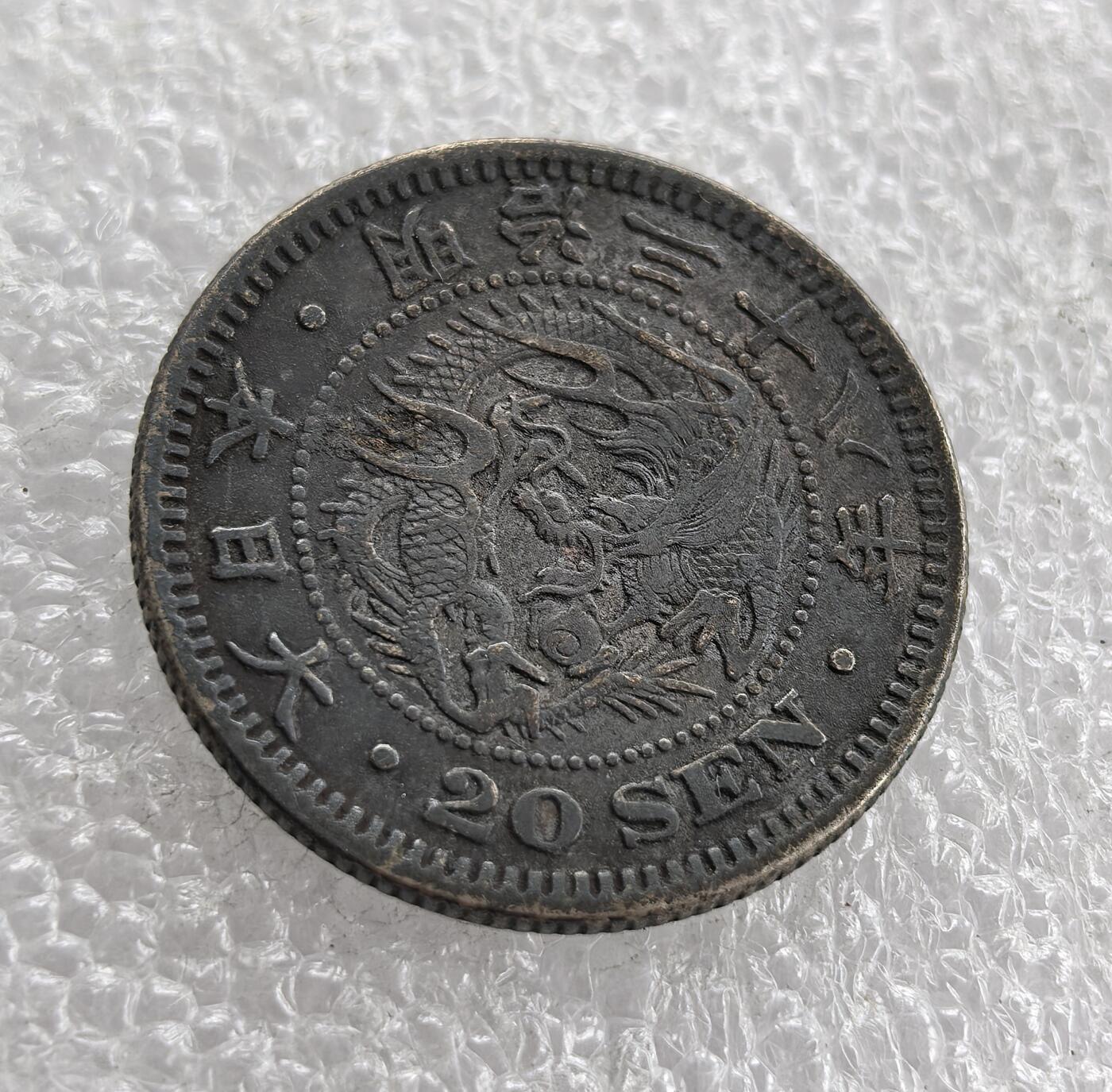 外国优质老铜币高银银币，周六九点倒数截拍，满百包邮，持续收拍 明治三十八年（1905 年）日本二十钱银币，正面皇室菊纹、“二十钱” 配桐叶花环，彰显皇权与传统；背面 “大日本 明治三十八年”、龙纹与 “20 SEN”，龙纹受中国文化影响。明治维新后日本币制改革，此币是近代化与对外扩张初期的货币见证。