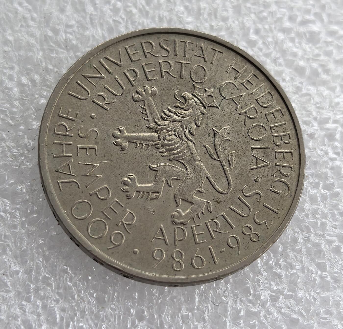 外国优质老铜币高银银币，周六九点倒数截拍，满百包邮，持续收拍 西德1986年5马克纪念币，正面铸联邦德国国徽（联邦之鹰），威严庄重；背面为海德堡大学 600 周年纪念，雄狮图案灵动，文字清晰，兼具国徽经典设计与名校历史纪念价值，收藏意义突出。