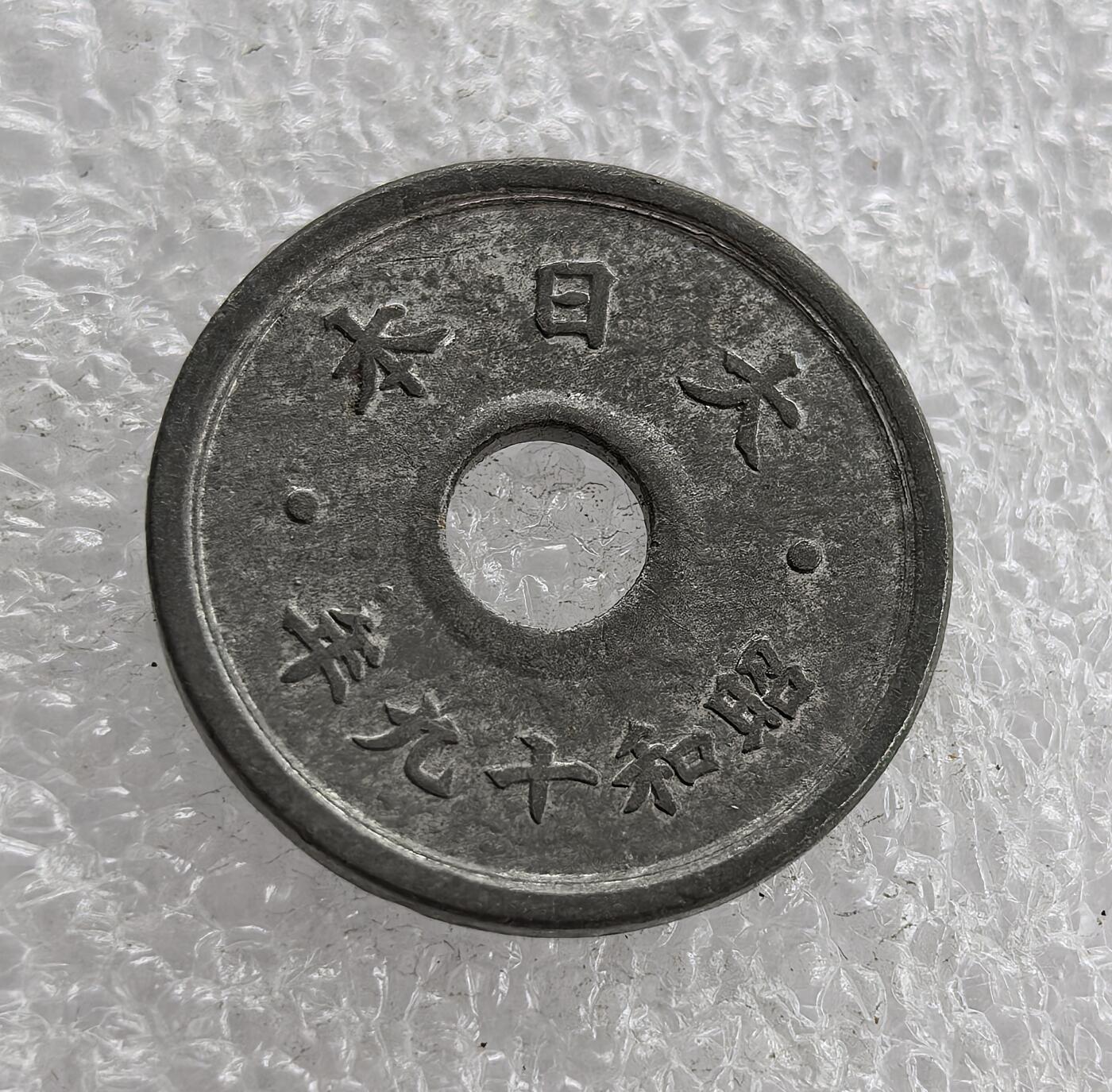 外国优质老铜币高银银币，周六九点倒数截拍，满百包邮，持续收拍 极美品昭和十九年（1944 年）日本十钱锡币，正面皇室菊纹、桐叶祥云纹彰显皇权与传统，圆孔形制节省材料；背面 “大日本”“昭和十九年” 标注国名年号，是二战末期日本金属匮乏、战时经济崩溃的货币见证。