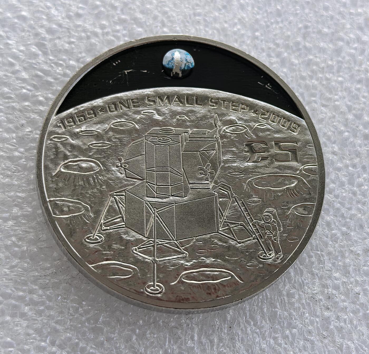 外国优质老铜币高银银币，周六九点倒数截拍，满百包邮，持续收拍 英属根西行政区 2009 年 5 镑纪念币，为纪念阿波罗 11 号人类首次登月 40 周年（1969-2009）打造。正面铸伊丽莎白二世头像与属地标识，背面刻画登月舱、宇航员登月球场景并镶嵌地球，铭文 “ONE SMALL STEP” 致敬登月壮举，属英联邦航天主题经典纪念币。